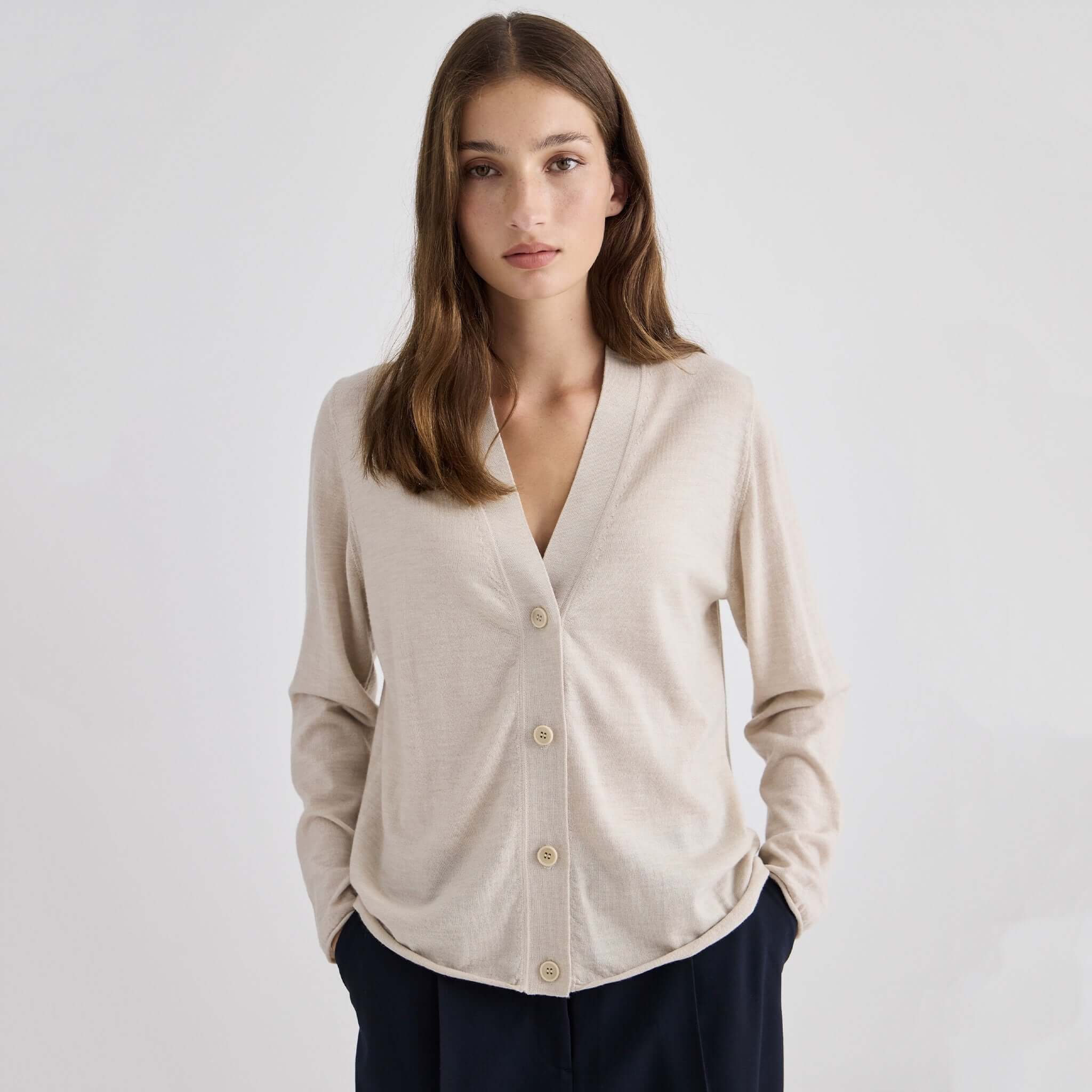 Laing Liv V-Neck Merino Cardigan - Sand worn by a model, showcasing its simple design and relaxed fit.