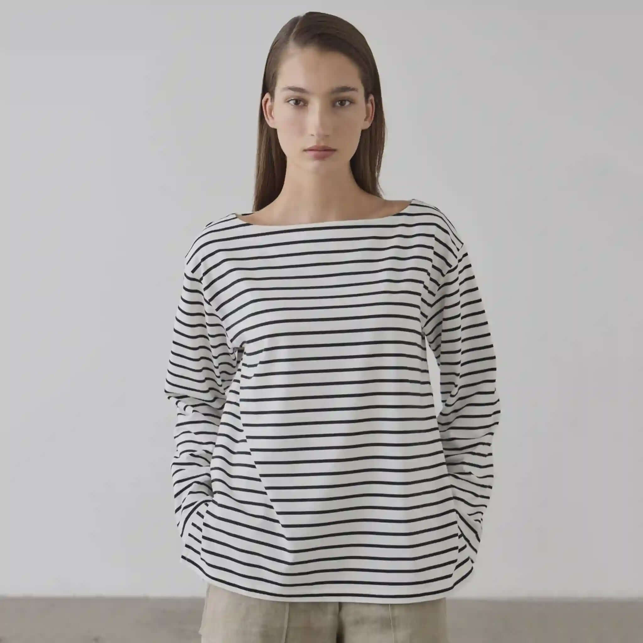 Woman wearing a black and white striped sweater against a plain background