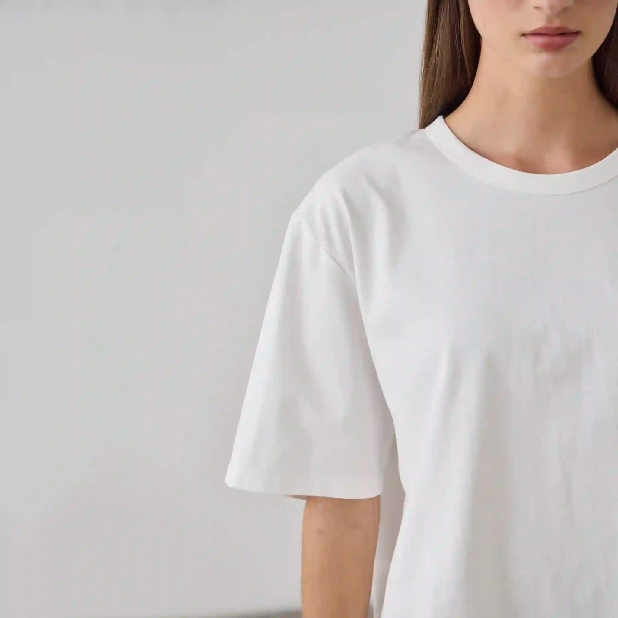 Person wearing a plain white t-shirt against a neutral background