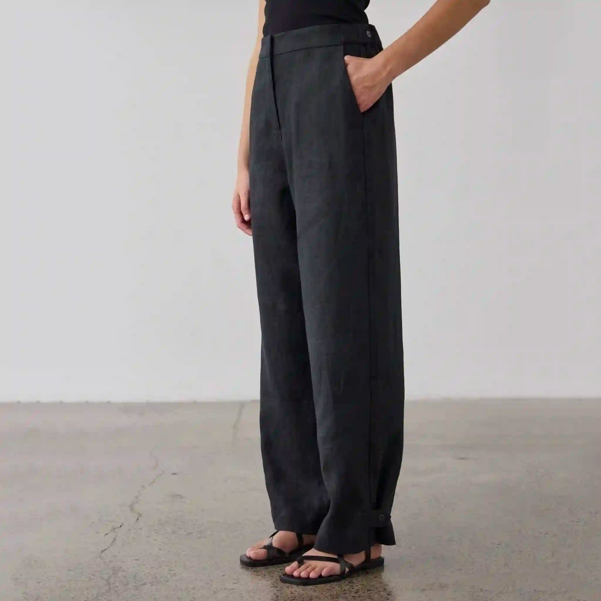 Person wearing dark gray wide-leg pants against a plain background