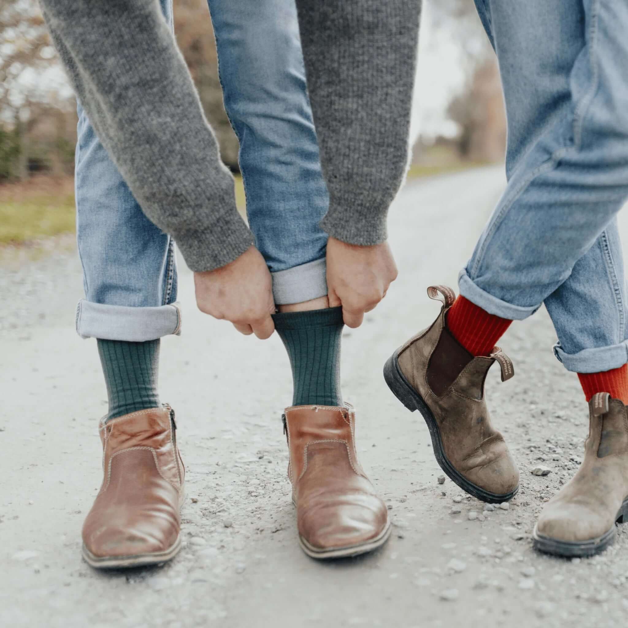 Lamington Merino Adult Crew Socks - Tuatara worn by two people on a gravel road with stylish boots.
