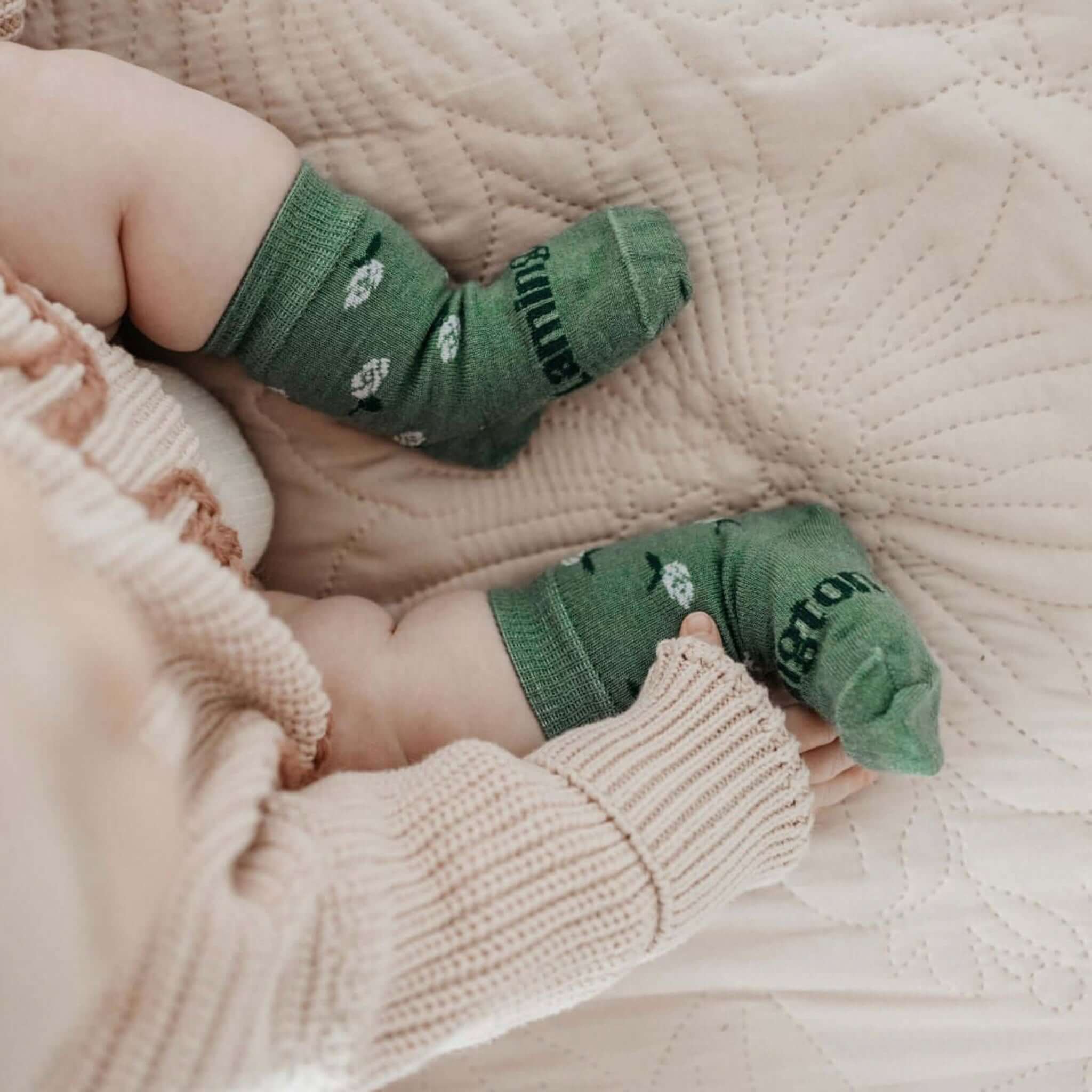 Lamington Merino Crew Baby Socks - Heather on a baby's feet, featuring sage green with white roses.