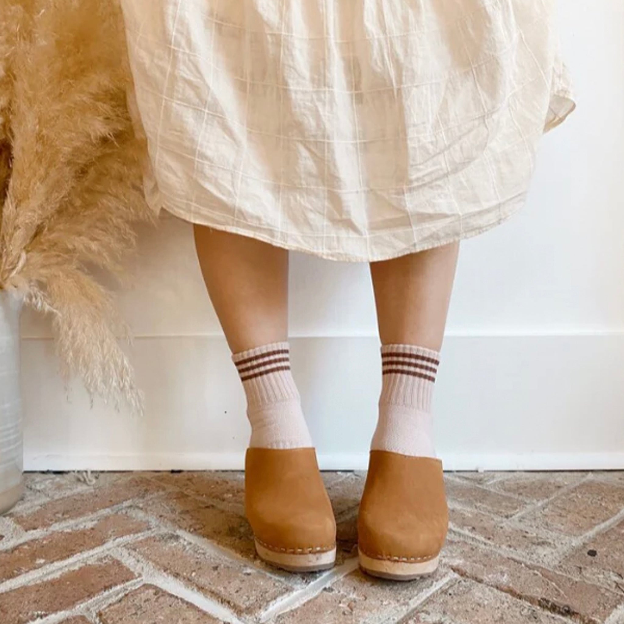 Person wearing a pair of pink socks with brown stripes and text that reads 'Le Bon Shoppe'.