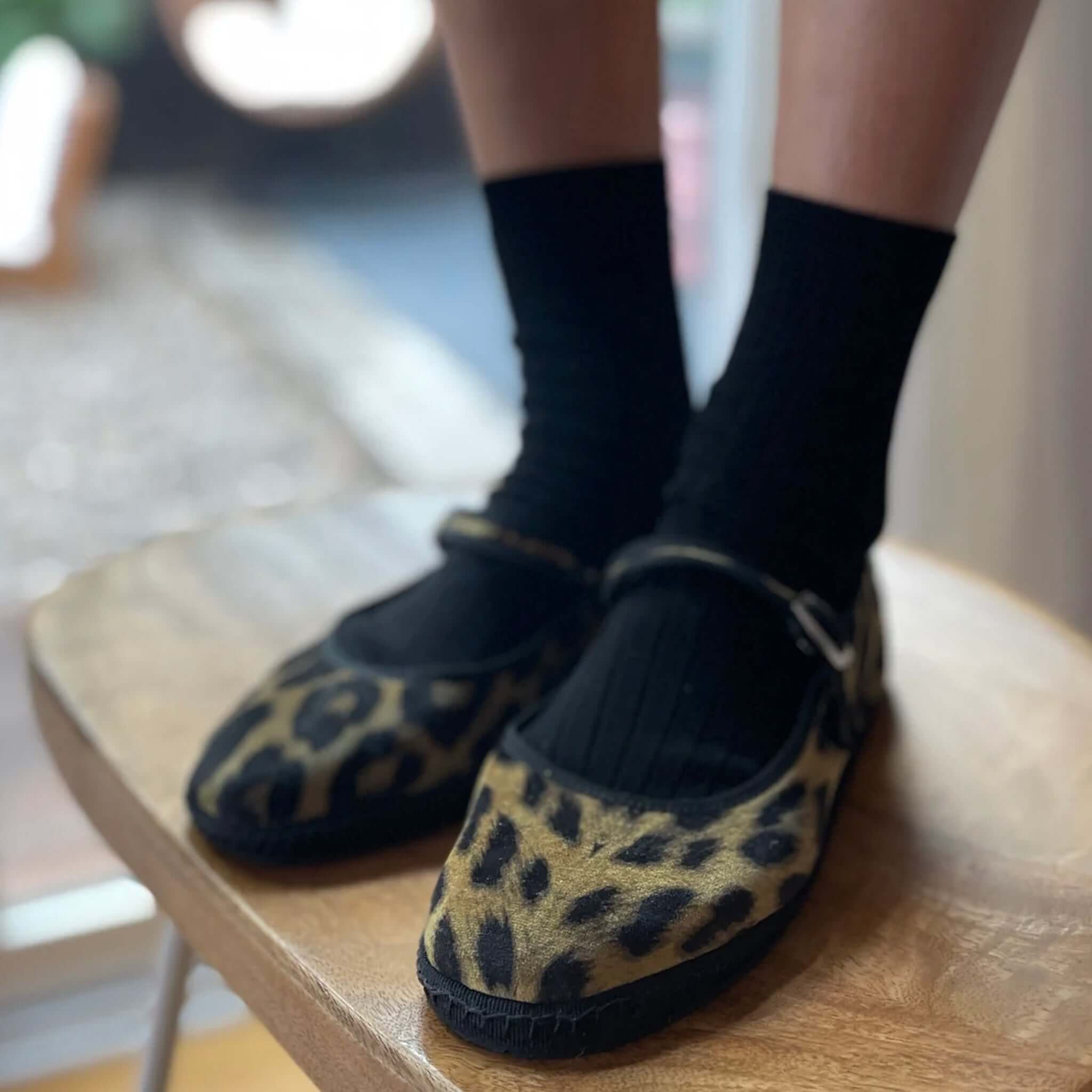 Le Bon Shoppe Her Socks - True Black worn with stylish leopard print shoes on a wooden table.