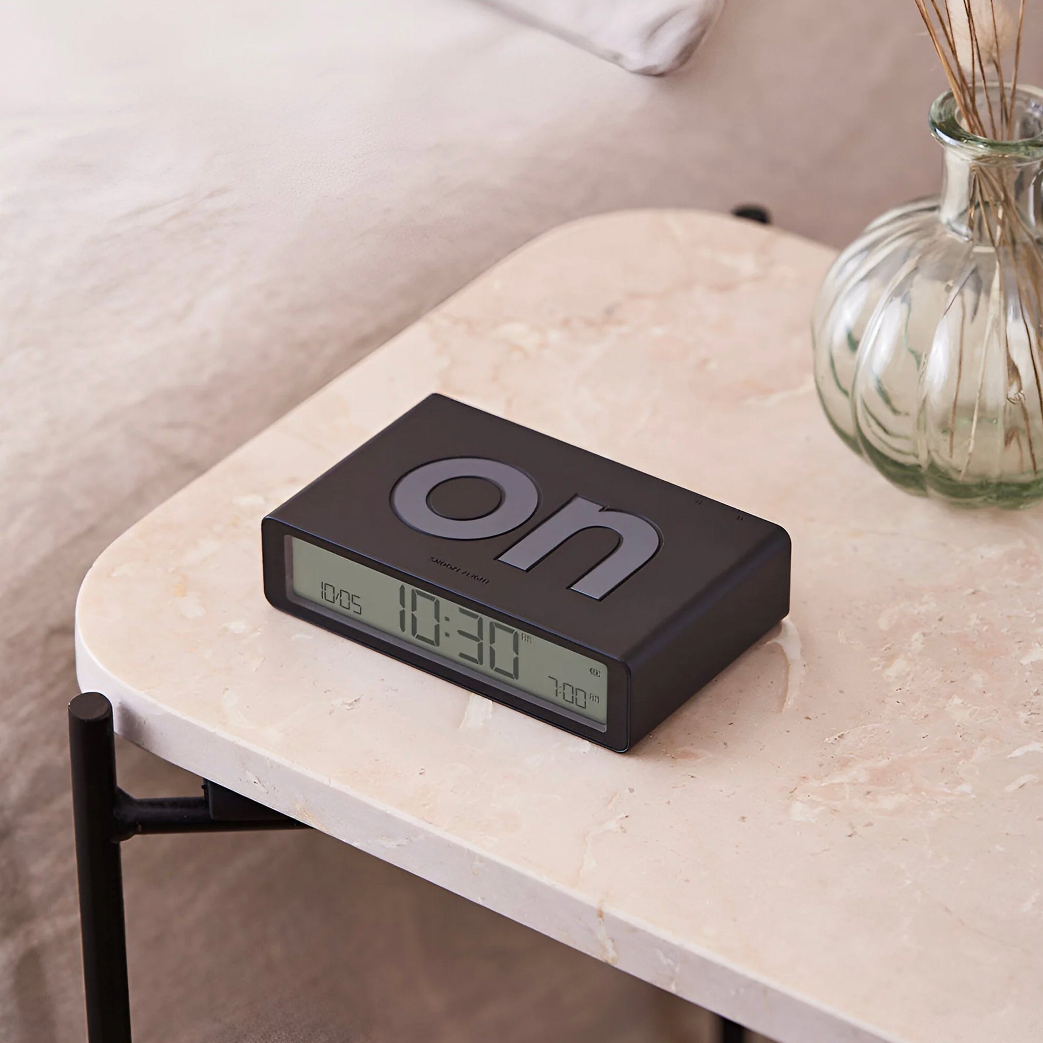 A black Lexon Flip Classic reversible LCD alarm clock displaying the time.