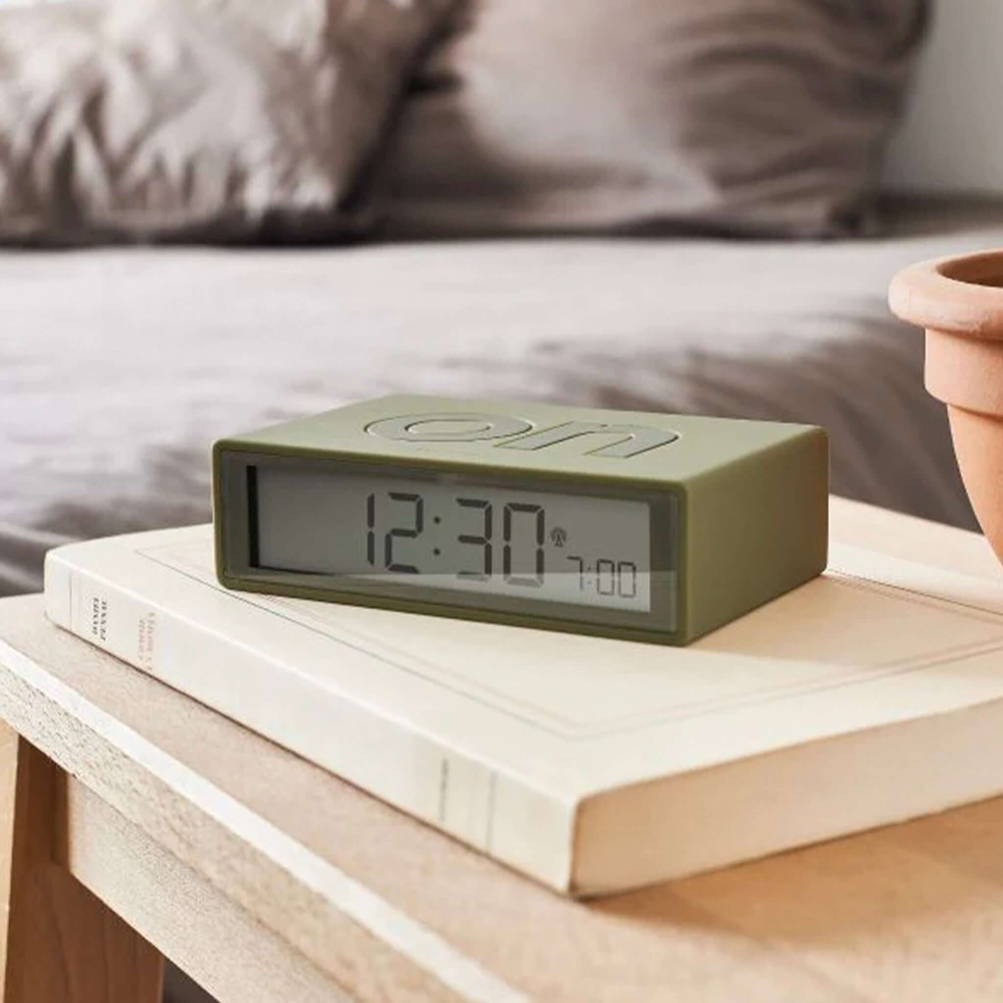 Khaki Lexon Flip Classic Reversible LCD Alarm Clock on a book.