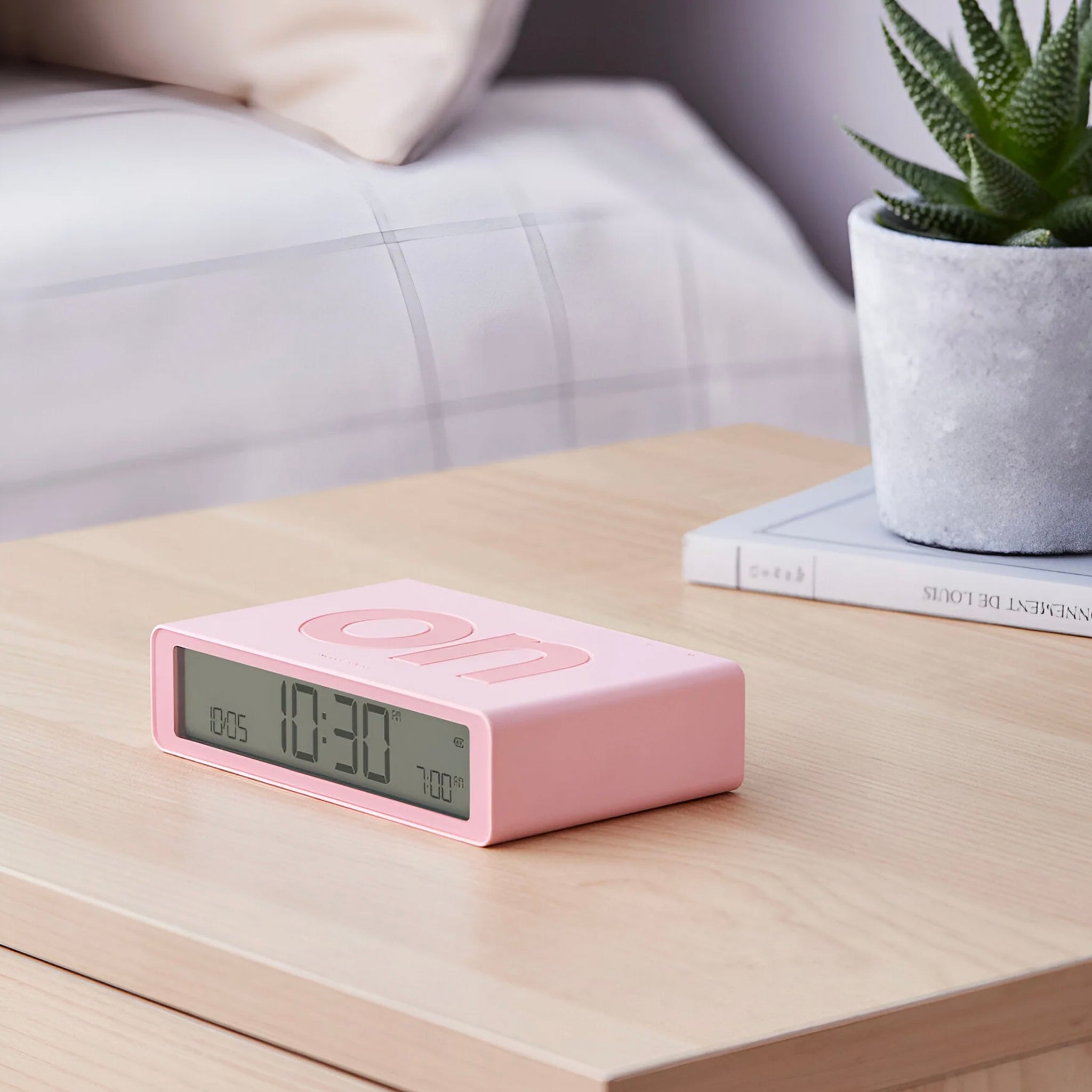 A pink Lexon Flip Classic Reversible LCD Alarm Clock displaying time on its screen.