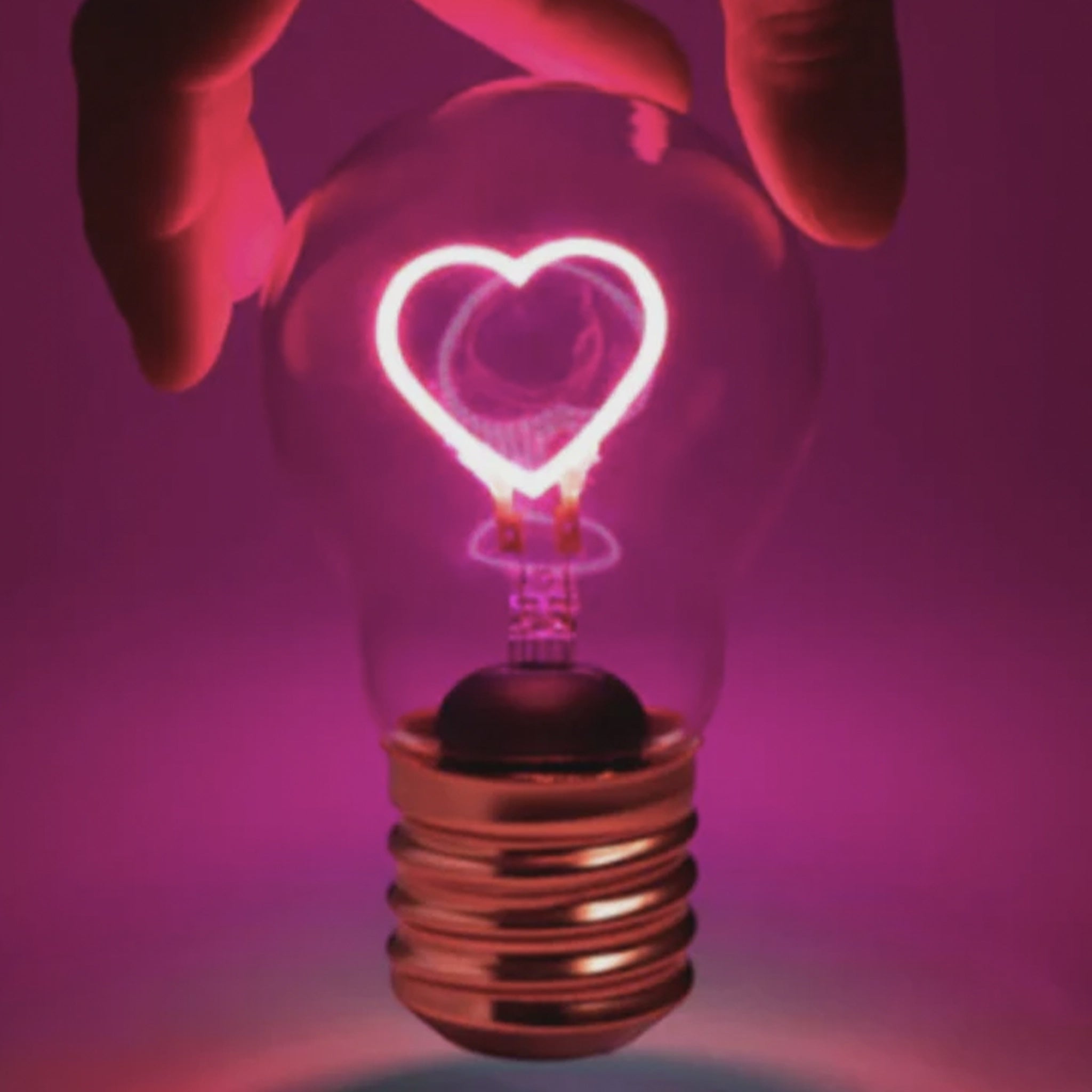 Light bulb with heart-shaped filament against a purple background