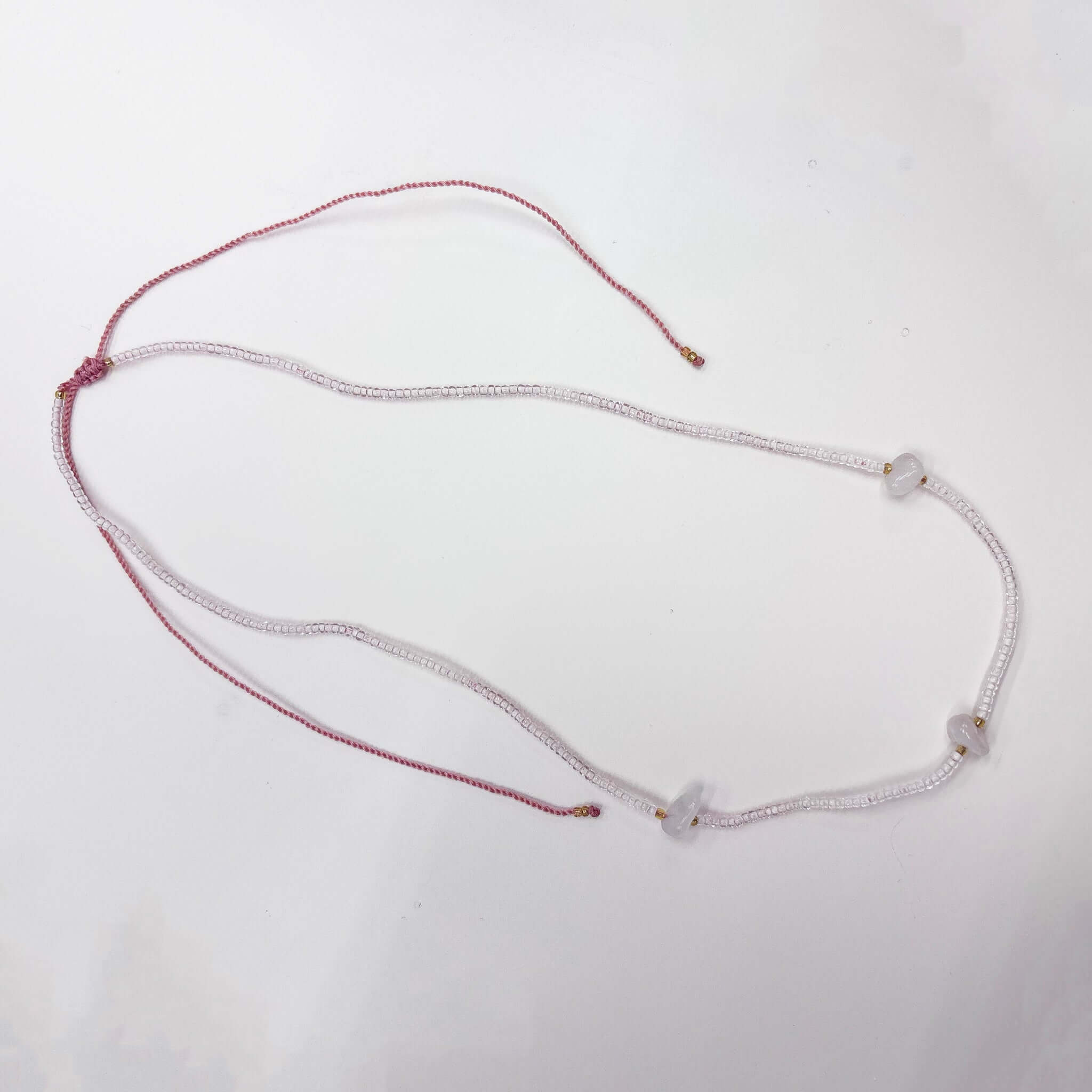 Margaret Elsie Necklace featuring pink crystal beads, natural stone chips, and gold spacers on an adjustable cord.