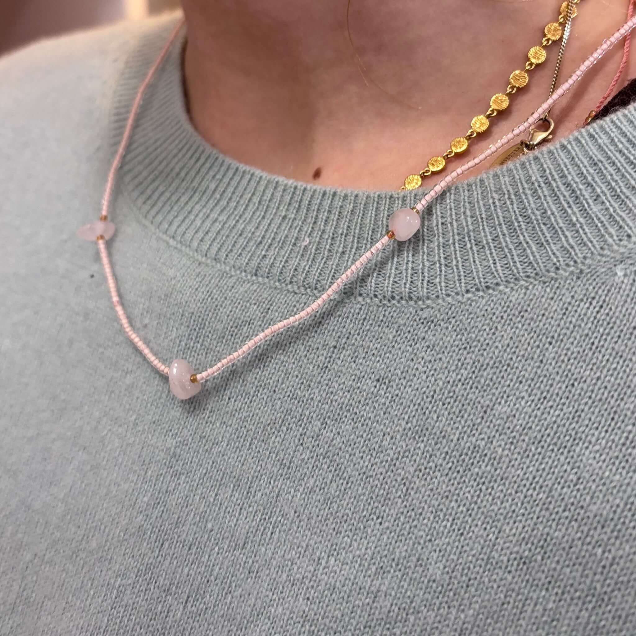 Close-up of a woman wearing the Margaret Elsie Necklace with pink crystal beads and gold spacers.