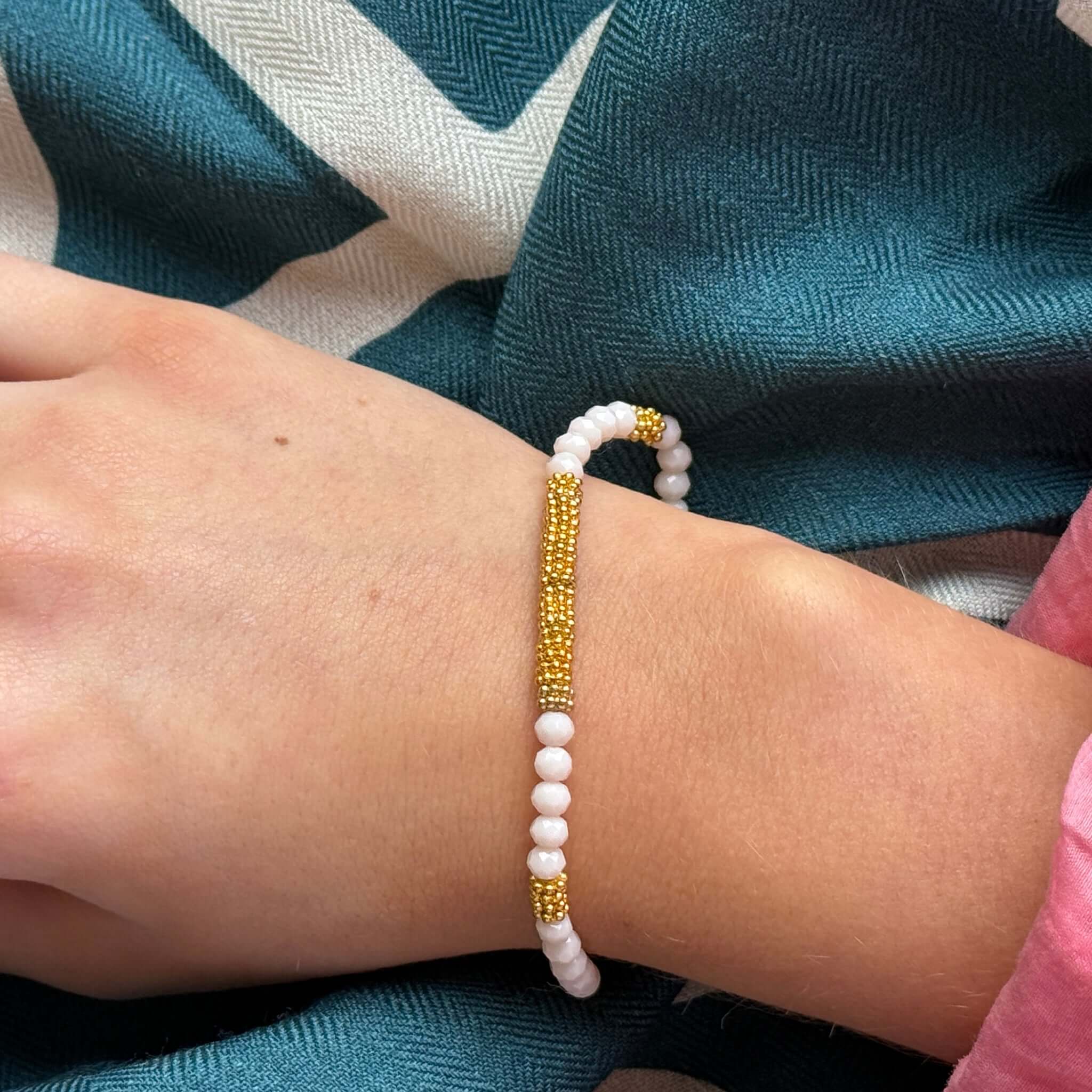 Margaret Lola Bracelet featuring white crystal beads and a woven gold bead bar centerpiece on a wrist.