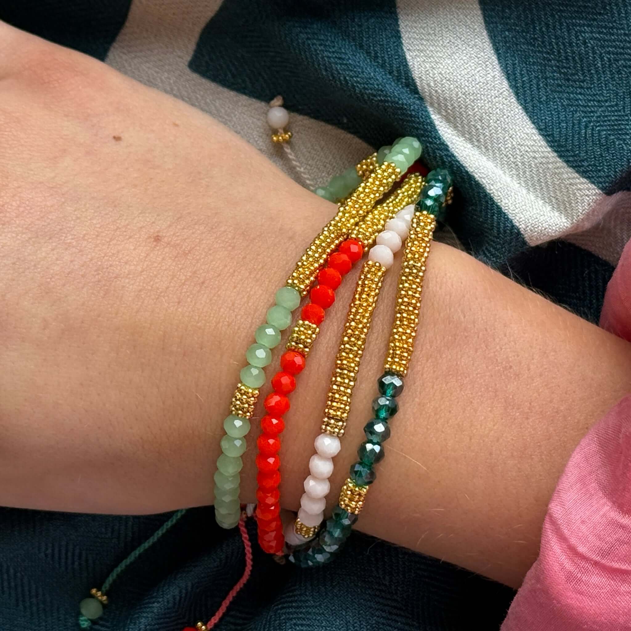 Margaret Lola Bracelet shown layered with colorful crystal beads and gold beads on a wrist.