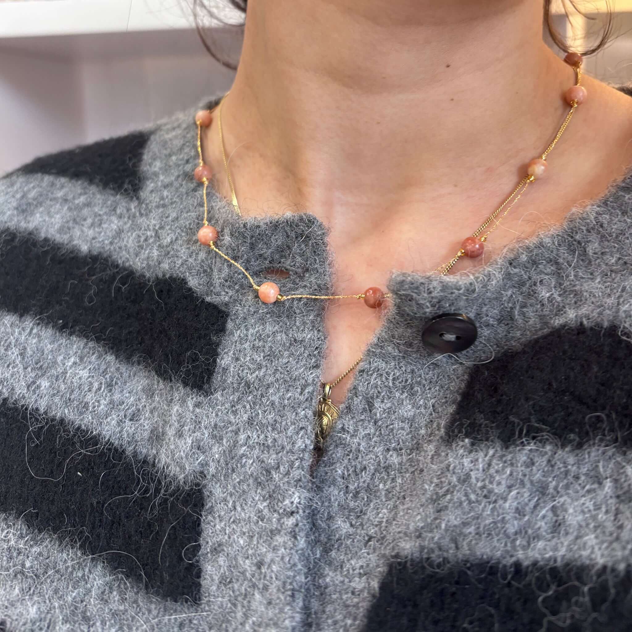 Margaret Loretta Necklace worn on a grey striped cardigan, showcasing smooth stone beads and a delicate gold chain.