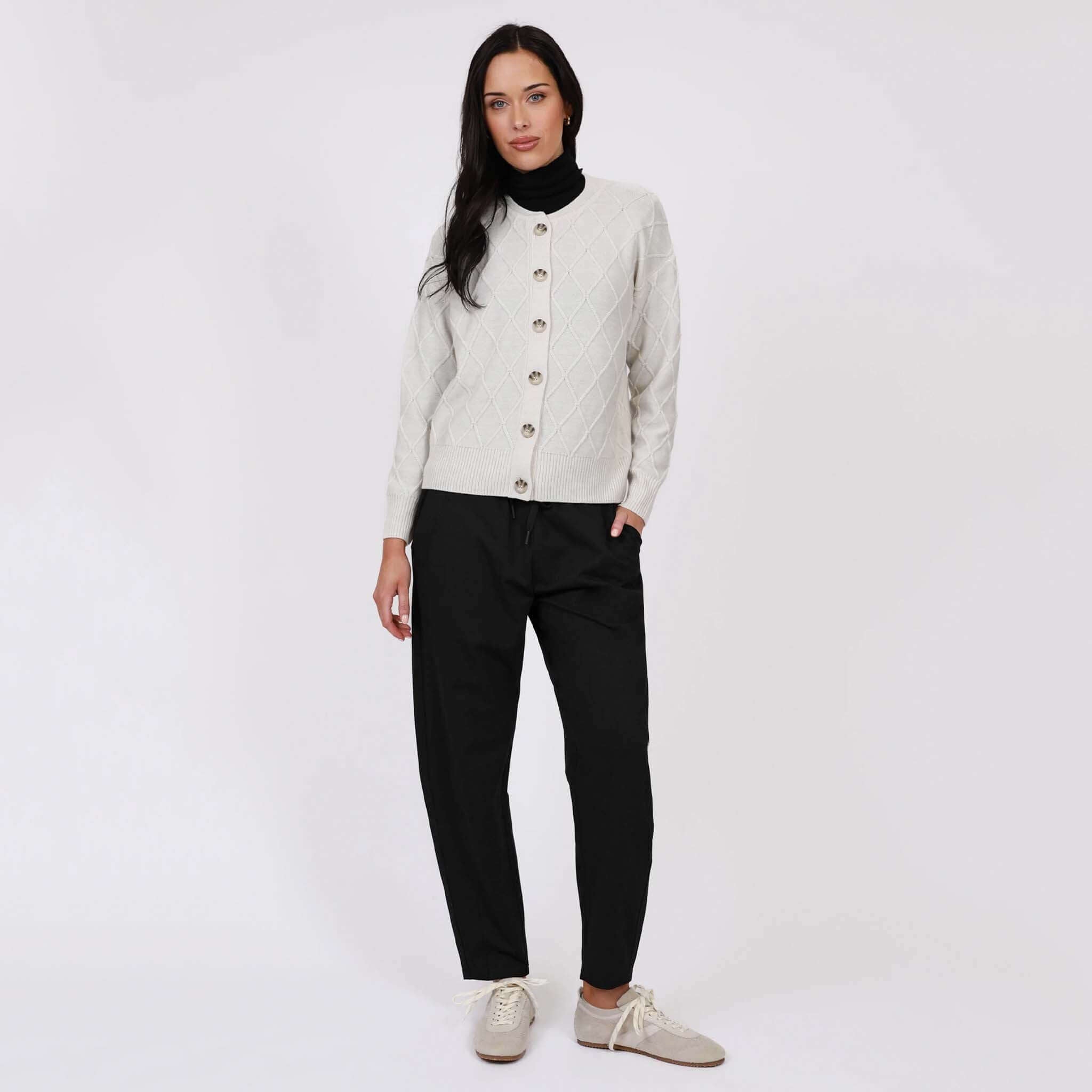 Marlow Barrel Trackie - Black being worn by a model with a stylish cream cardigan and turtleneck, showcasing relaxed fashion.
