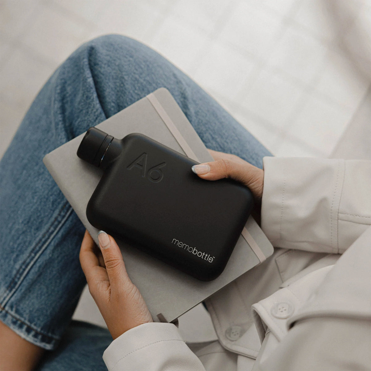 Memobottle A6 Stainless Steel - Black held in hand on a notebook, lifestyle view