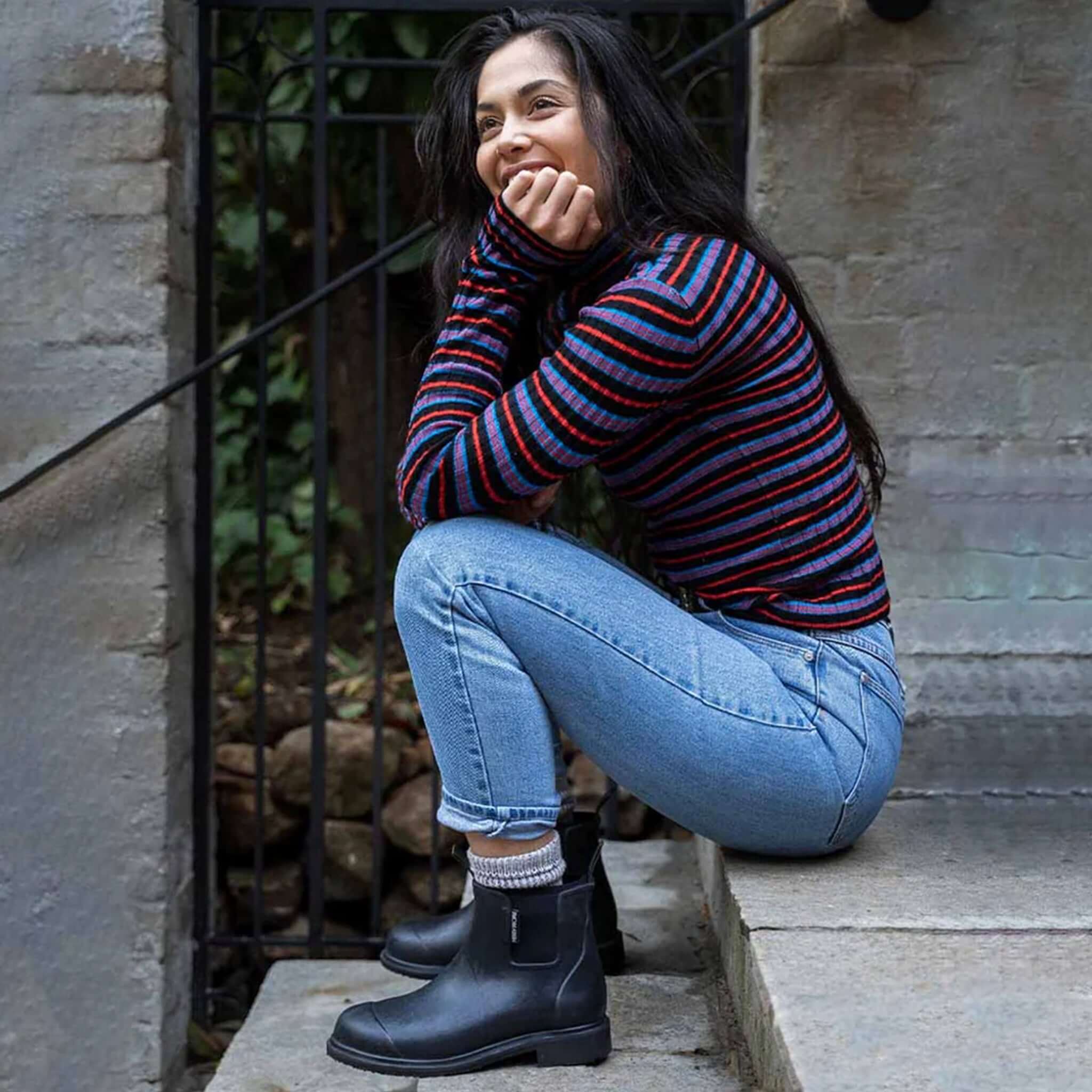 Alt Tag: Merry People Bobbi Ankle Boots - Black worn by woman crouching outdoors, waterproof natural rubber rain boots with neoprene lining