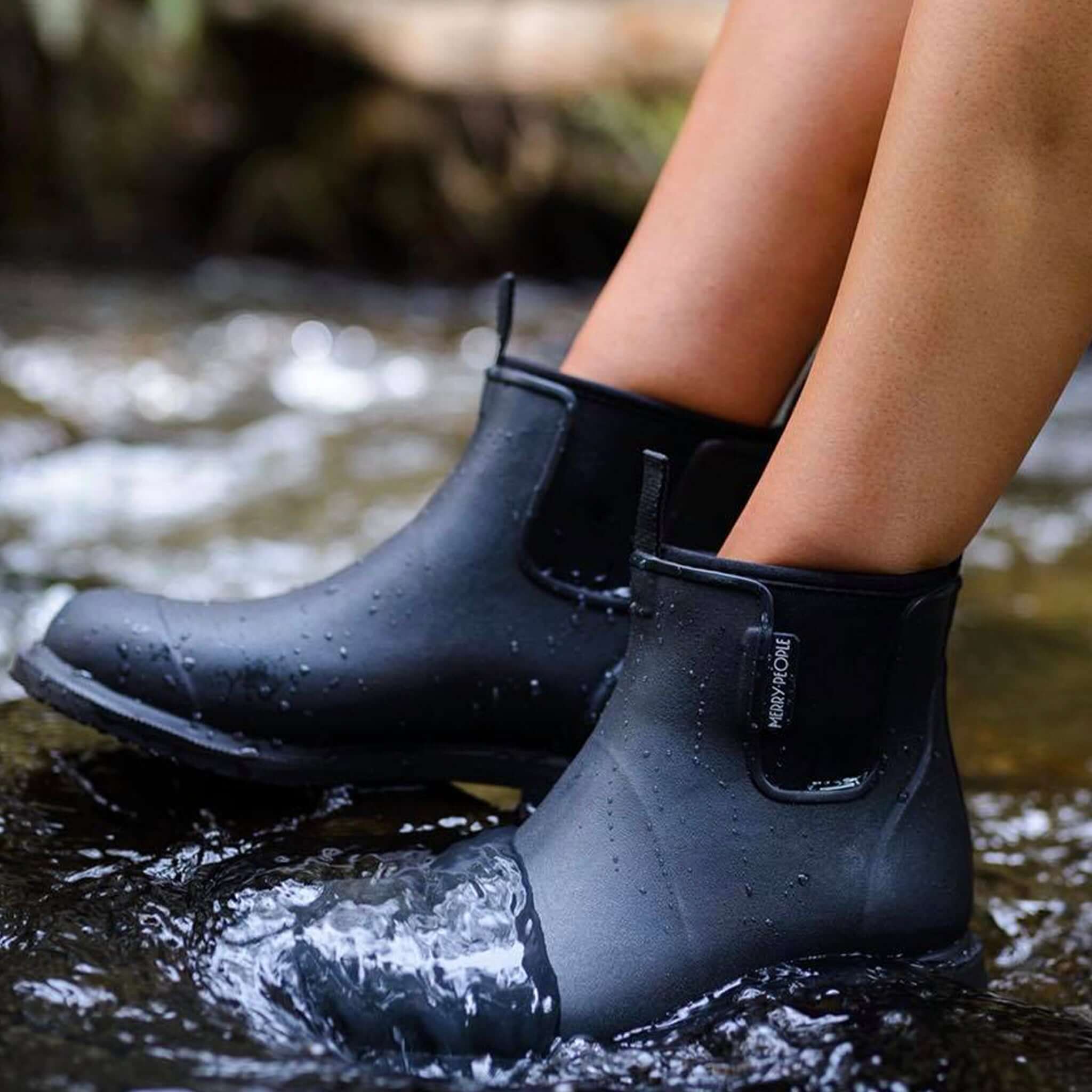 Merry People Bobbi Ankle Boots - Black worn in water for stylish rain protection.