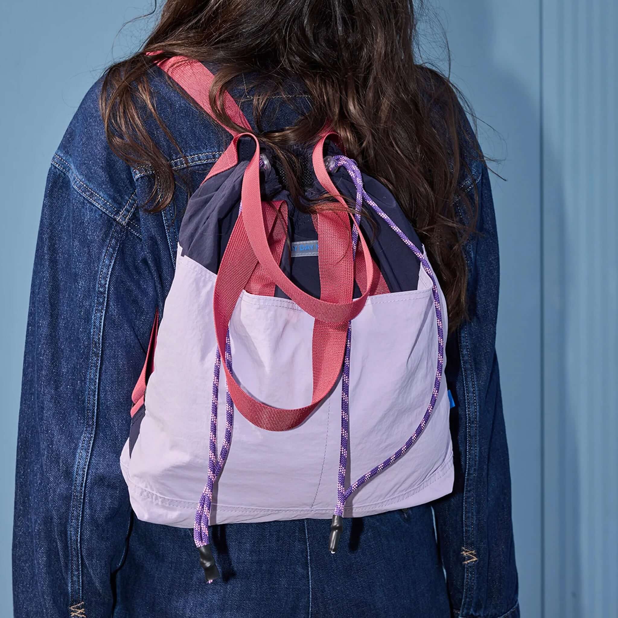 Milligram Any Day Now Any Day Backpack - Lilac & Plum worn by a model, showcasing its colorblock design.