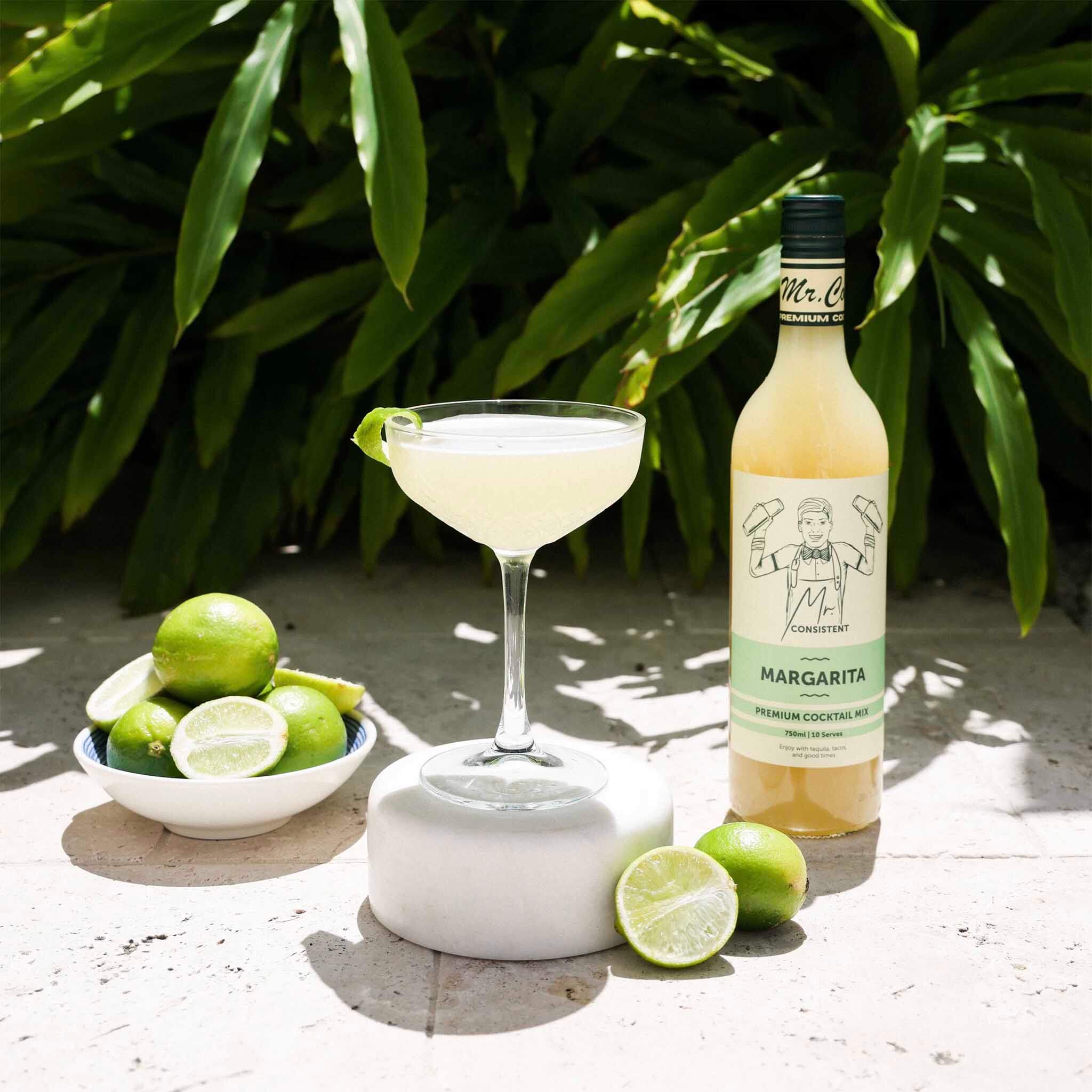 Mr. Consistent Margarita Cocktail Mixer with cocktail and limes, perfect for refreshing margaritas.