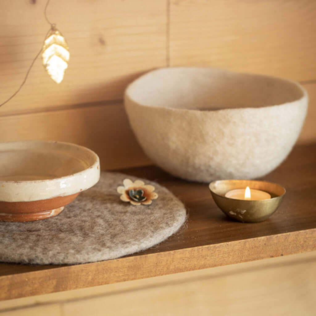 Muskhane Felt Bowl - Natural on wooden shelf with candle and ceramic bowls, handcrafted felt storage bowl decor