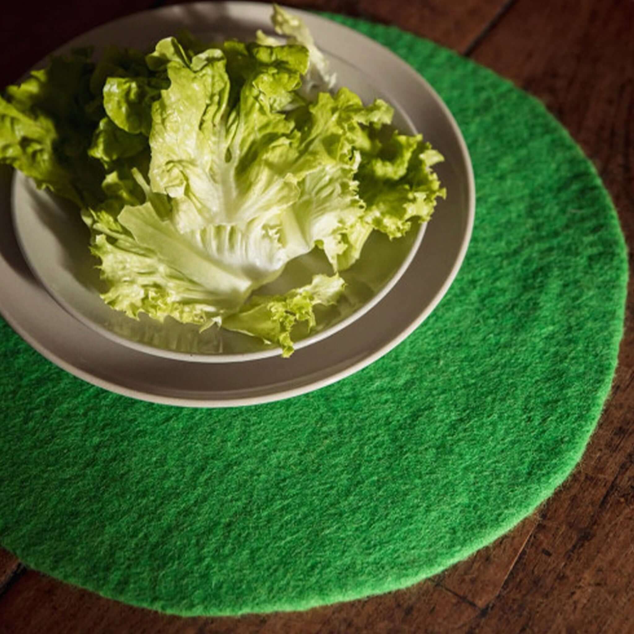 Alt Tag: Muskhane Felt Plain Round Placemat - Green Large green felt round placemat with plate on wooden table