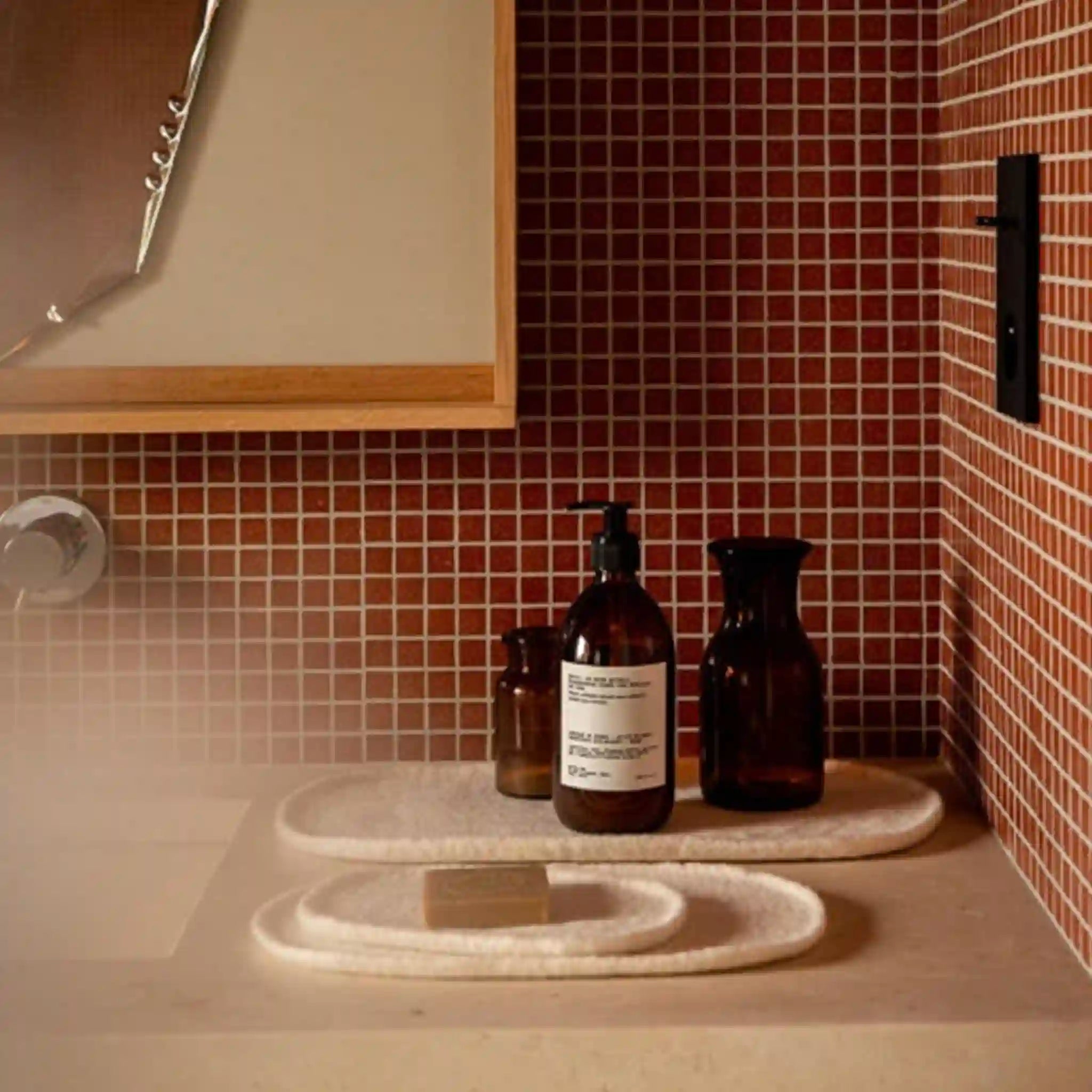 Bathroom setting with bottles and a soap bar on a shelf against a tiled wall.