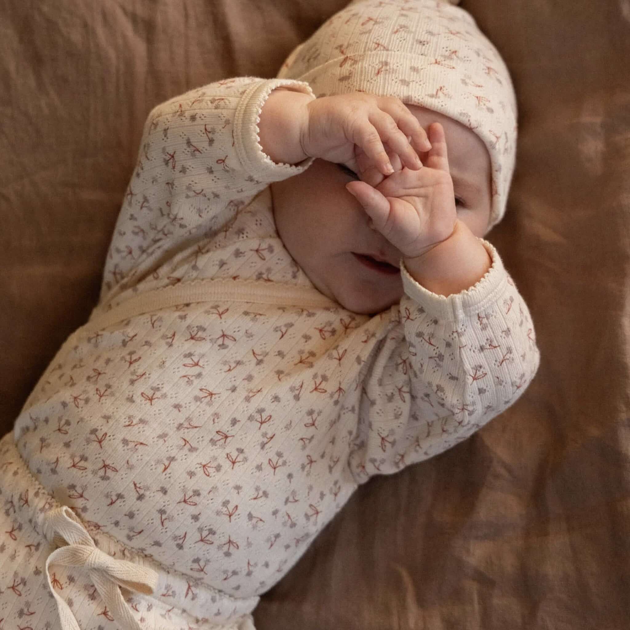 Nature Baby Organic Cotton Knotted Beanie - Pointelle Dandelion on a baby, showcasing softness and comfort.