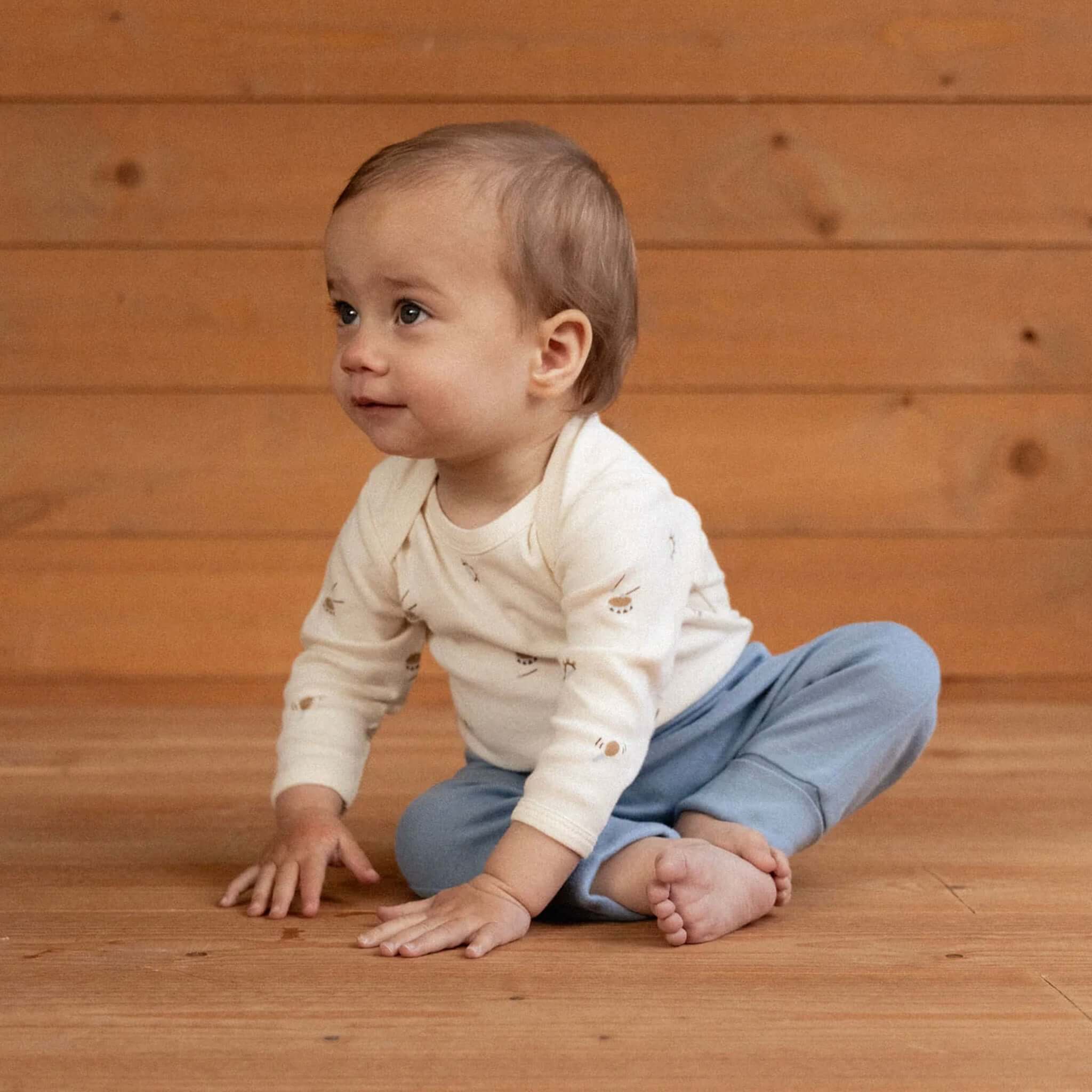 Nature Baby Organic Cotton Drawstring Pants - Jetty on a baby sitting on wooden floor, showcasing the soft blue color.