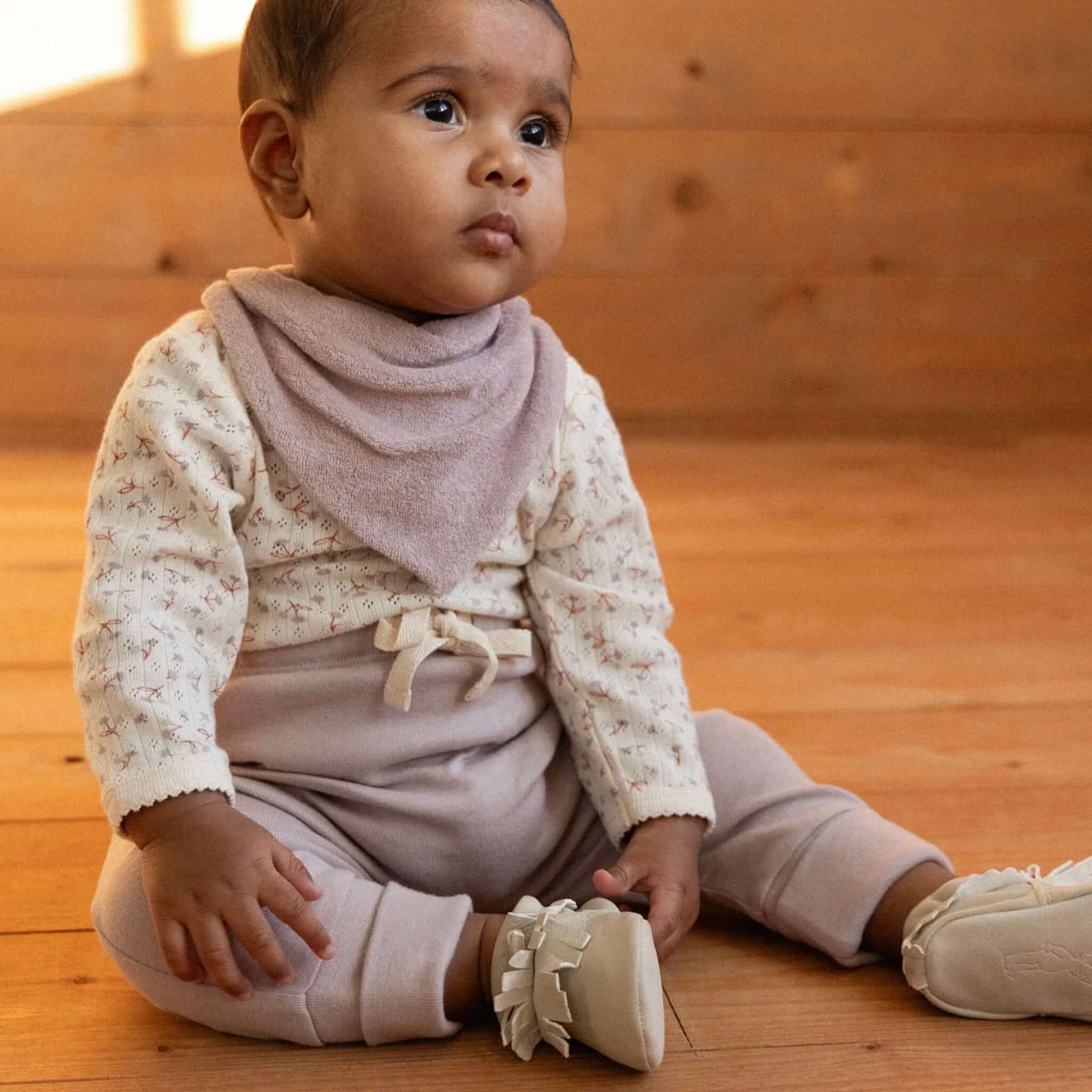 Nature Baby Organic Cotton Drawstring Pants - Lilac on baby sitting on wooden floor, wearing matching accessories.
