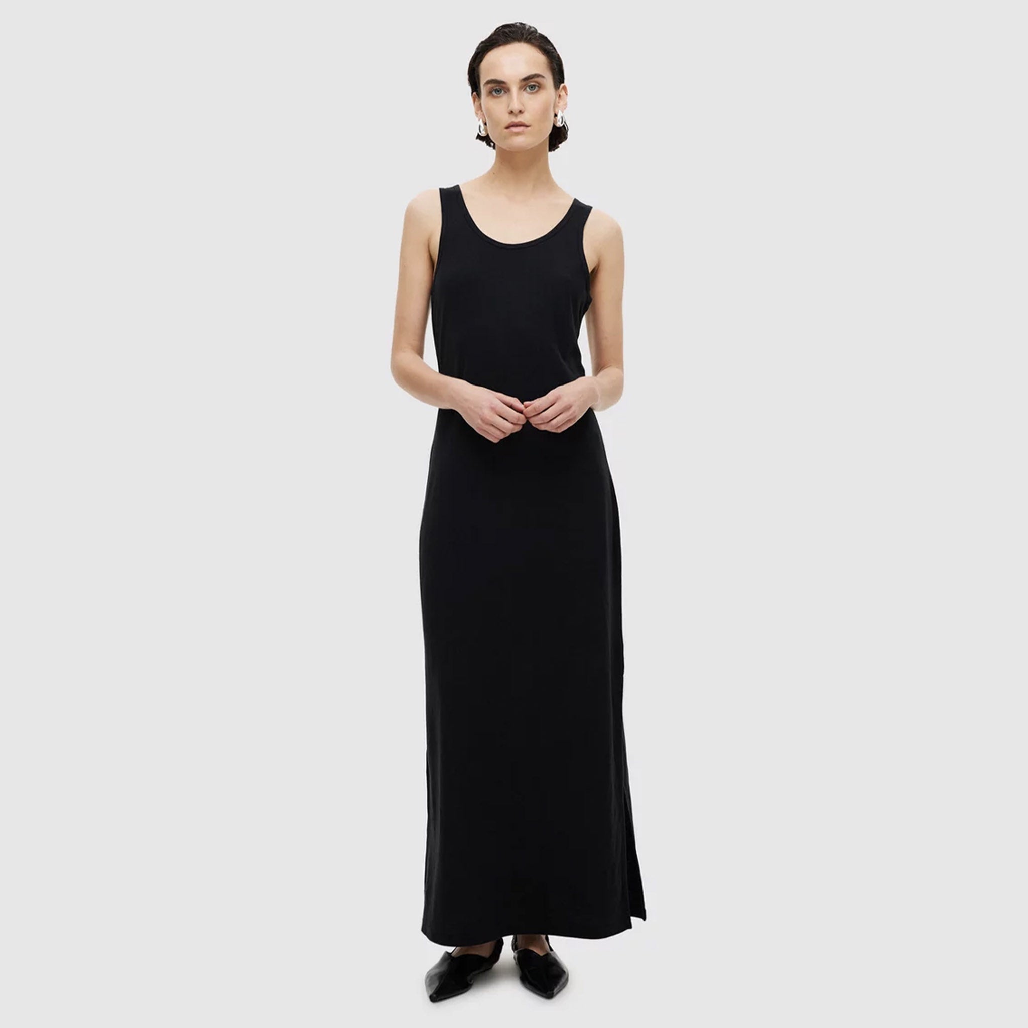 A model wearing a black maxi-length tank dress with a scoop neckline and tank-style straps.