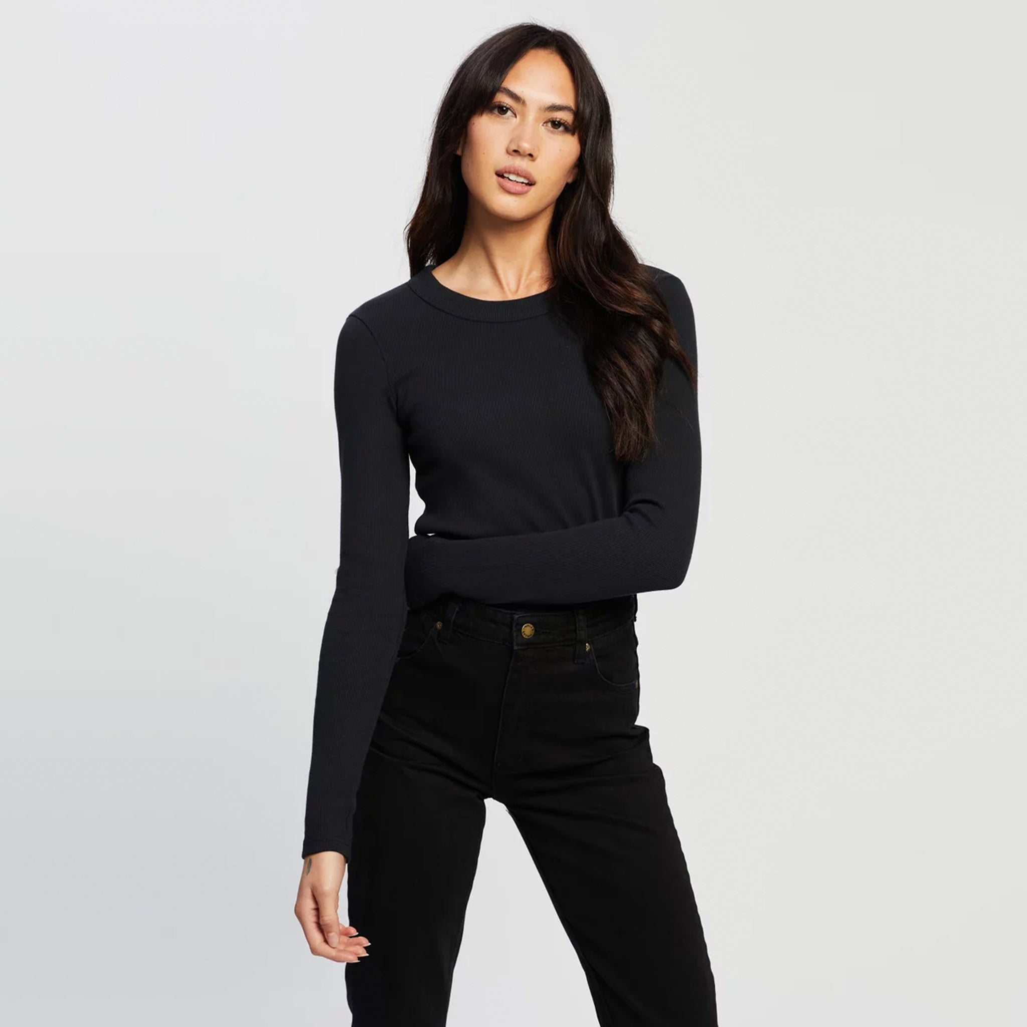 A person wearing a black long-sleeve top made from organic cotton, posing against a white background.