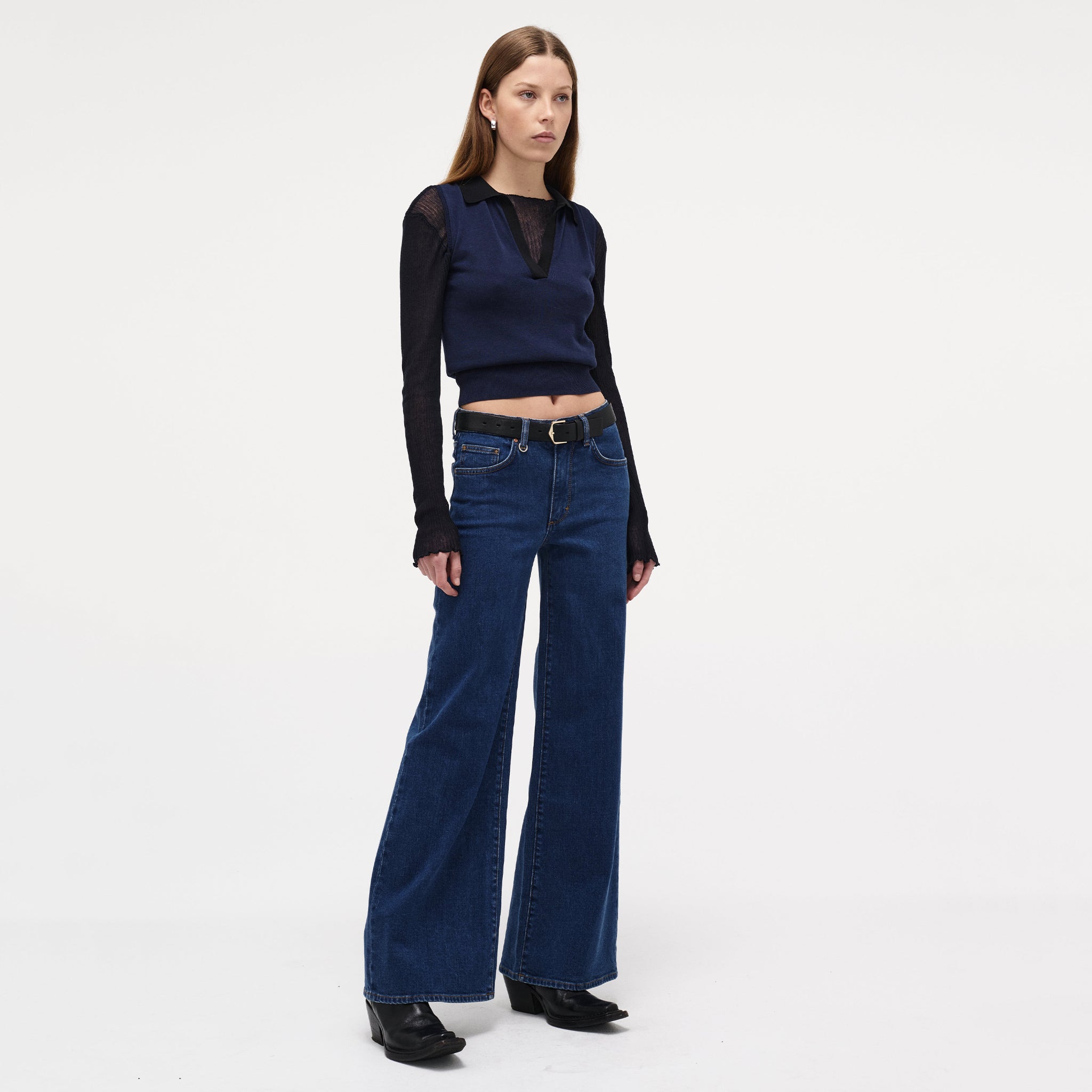 Woman wearing a navy top and blue jeans on a white background