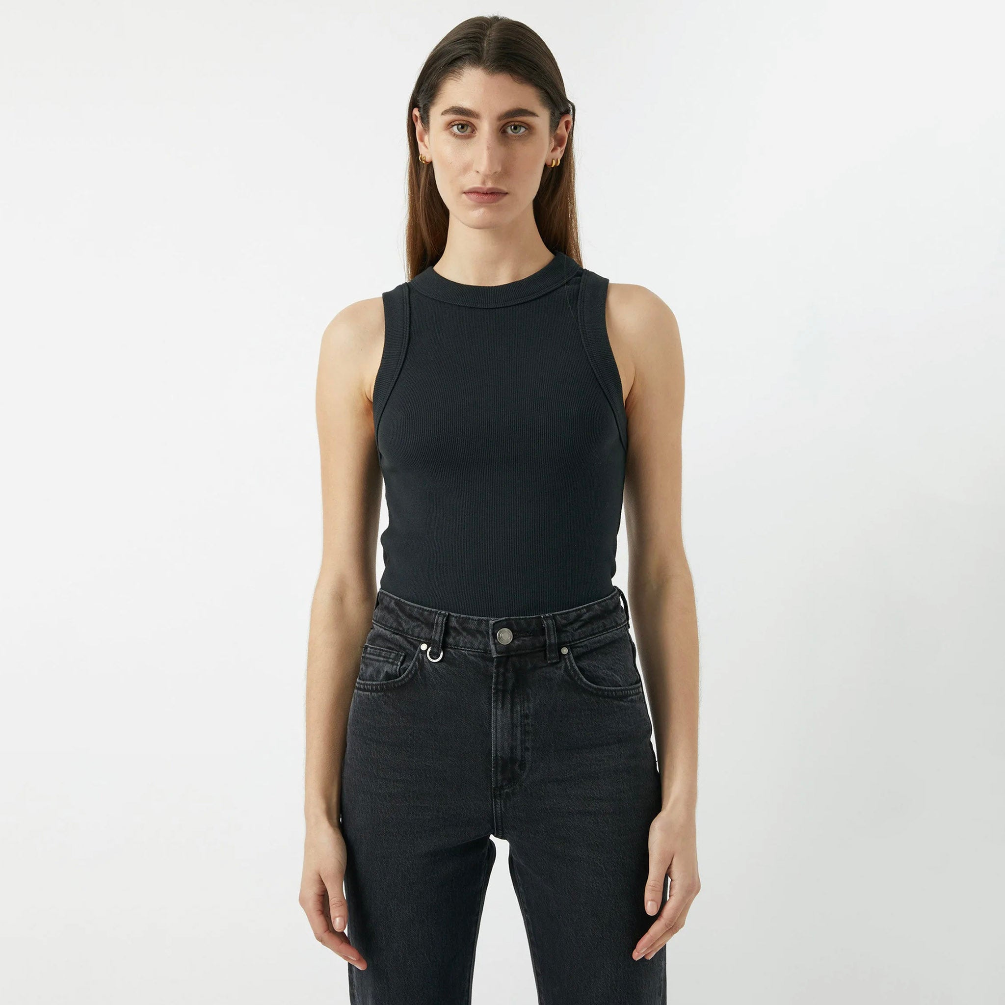 A female model wearing a black singlet and jeans. The singlet is sleeveless with a slim fit and wide rib binding at the hem.
