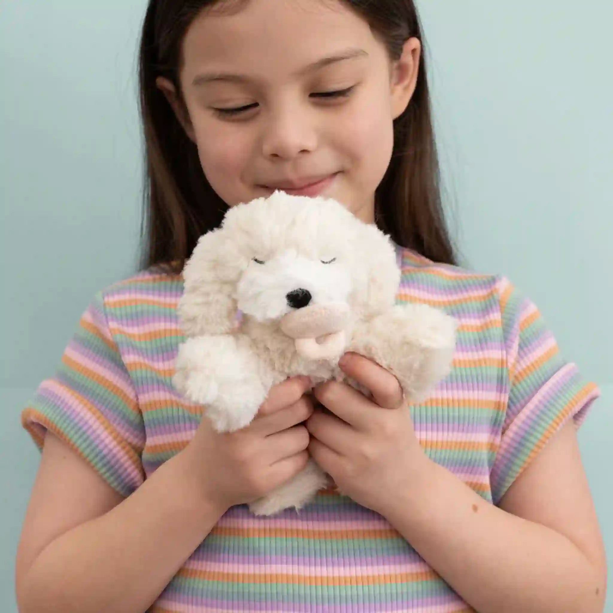 Young girl holding a white fluffy toy against a light blue background