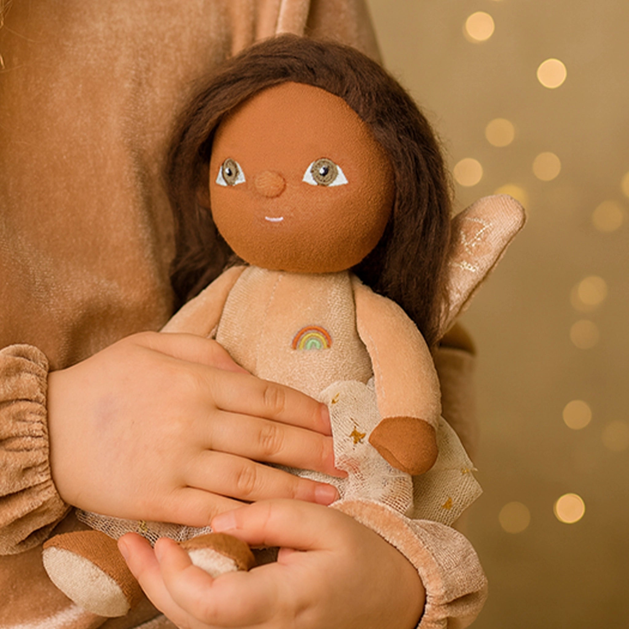Child holding a doll with a soft, warm background