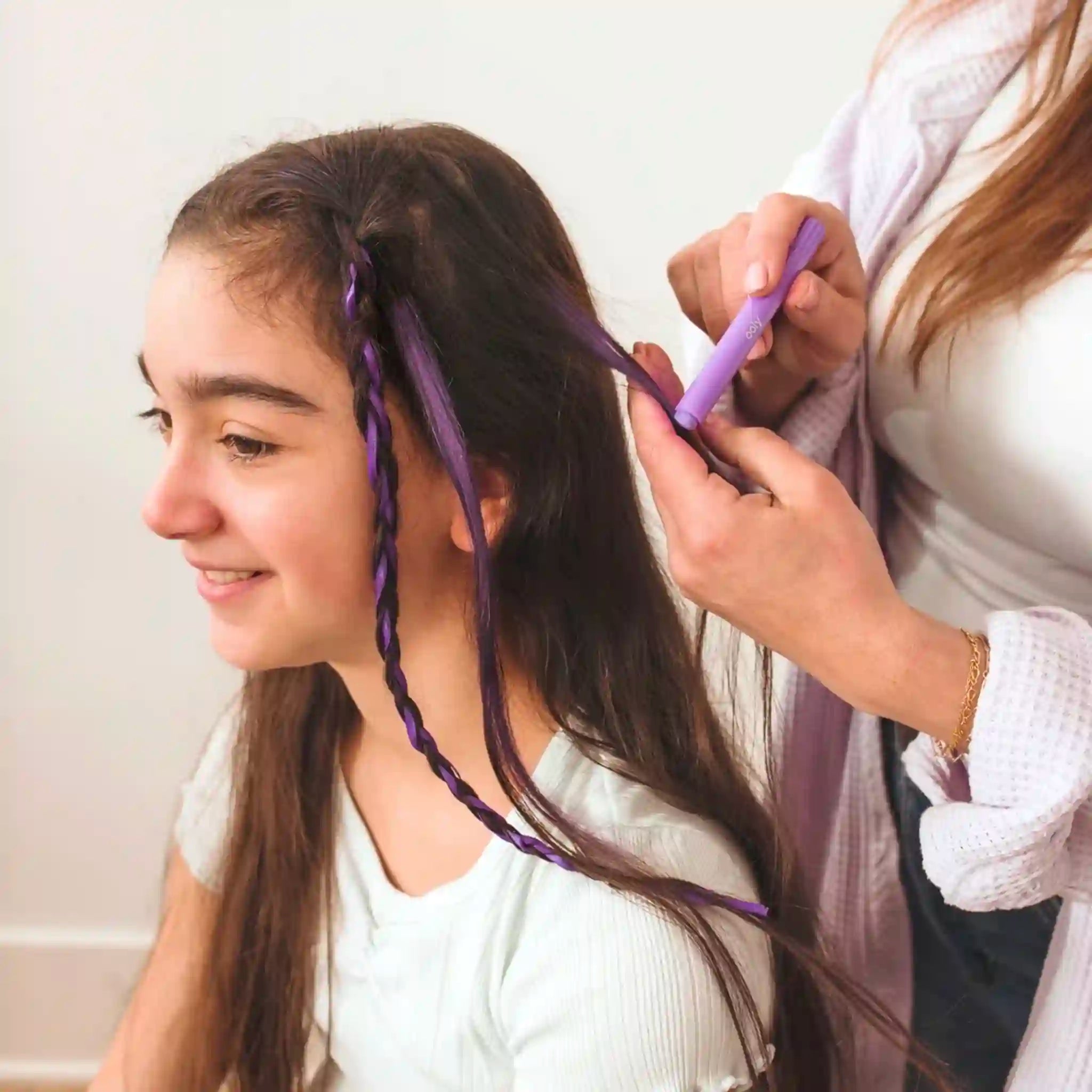 Person braiding another person's hair with purple hair extensions.