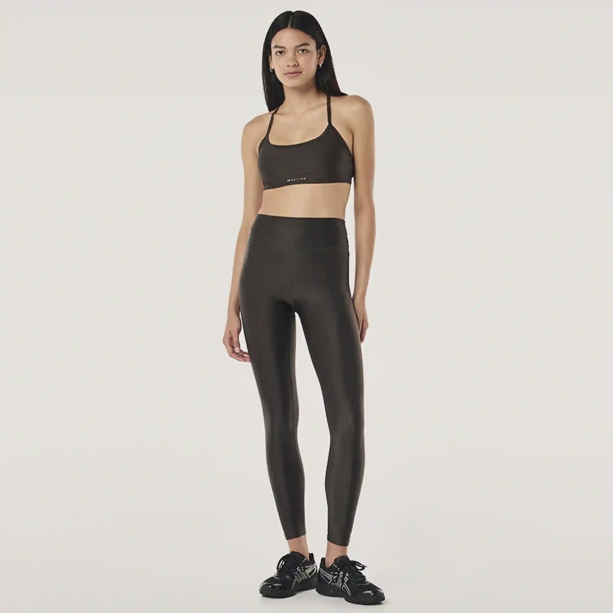 Woman wearing a black sports bra and leggings set on a white background