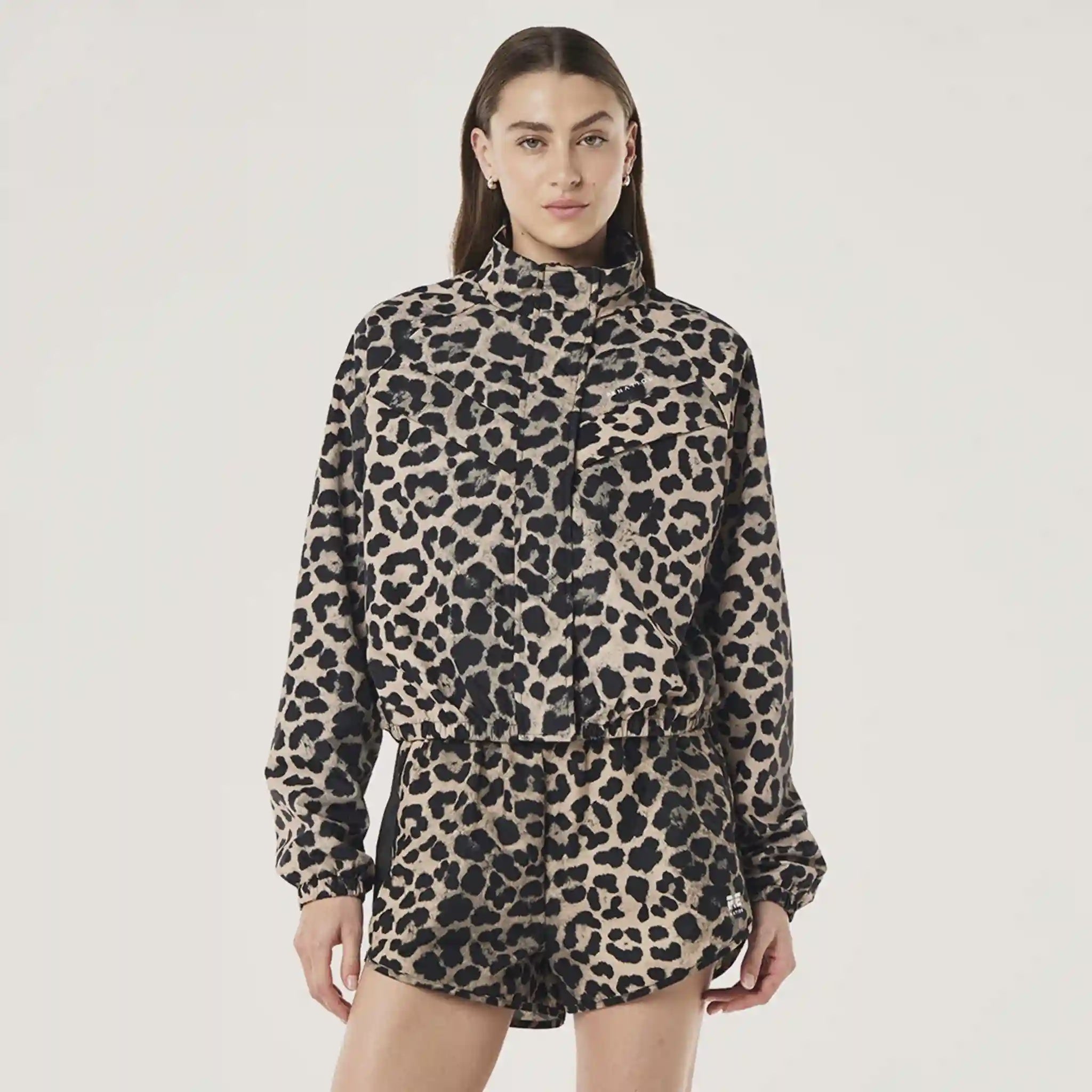 Person wearing a leopard print jacket and shorts on a plain background