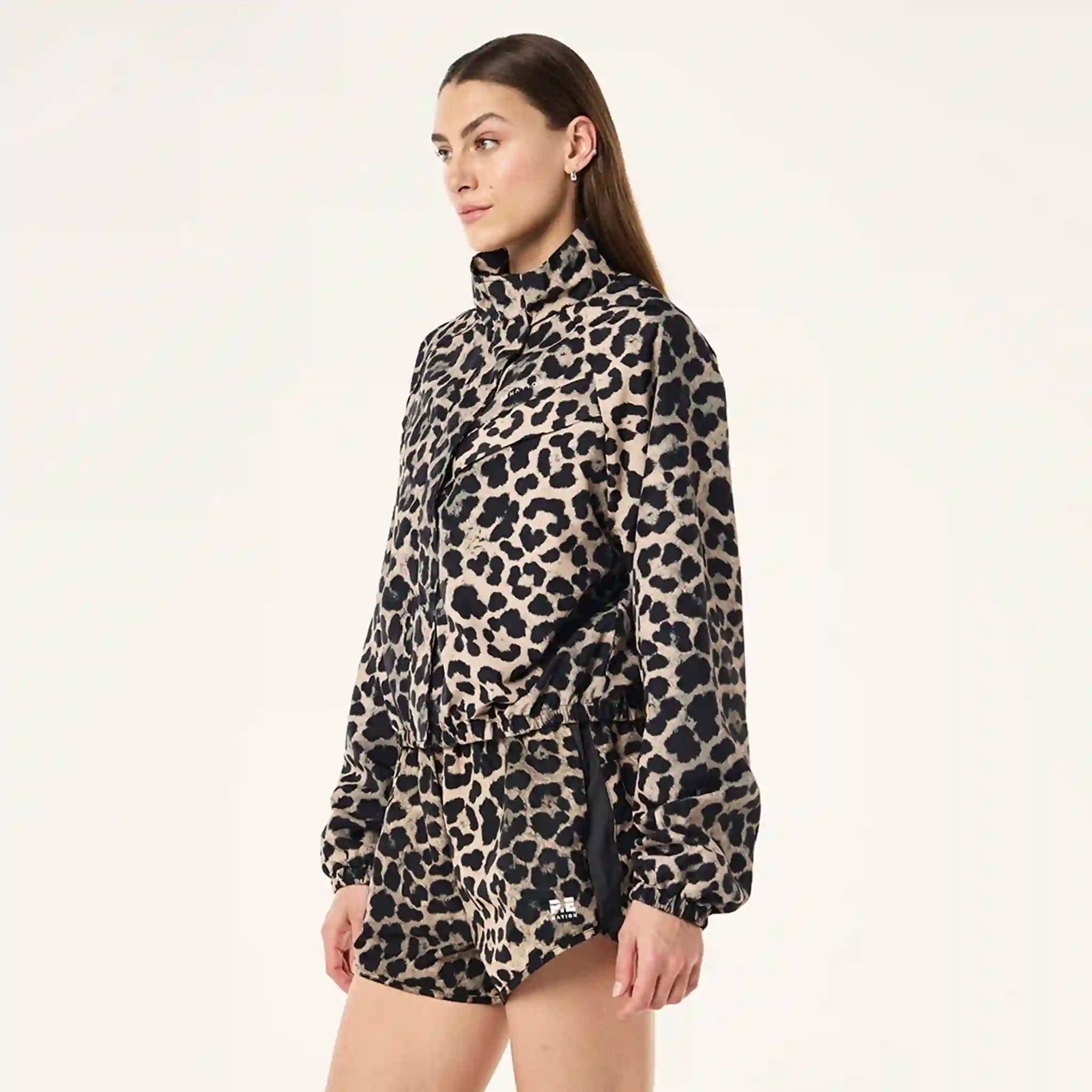 Person wearing a leopard print jacket and shorts on a plain background