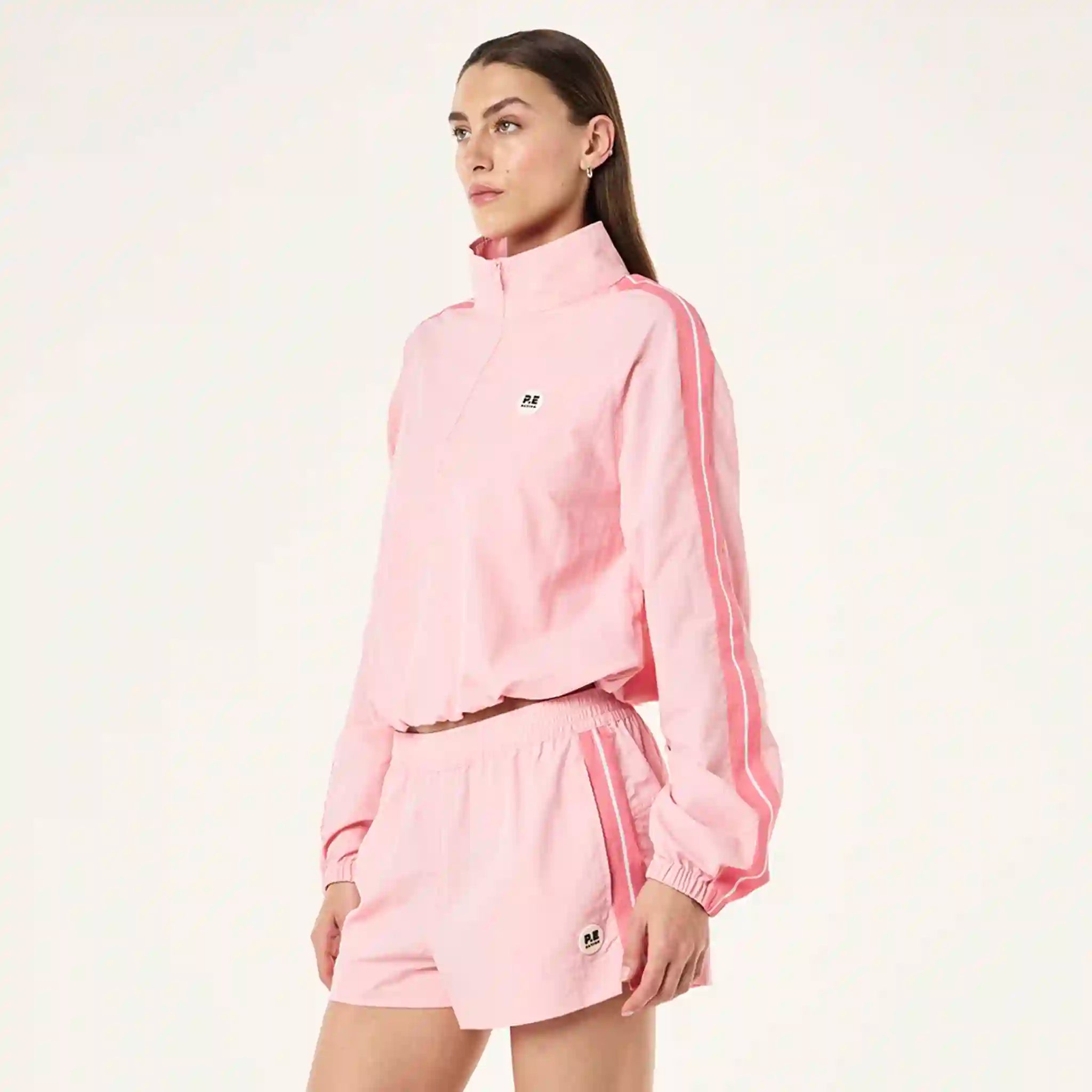 Person wearing a pink tracksuit with a brand logo on a white background
