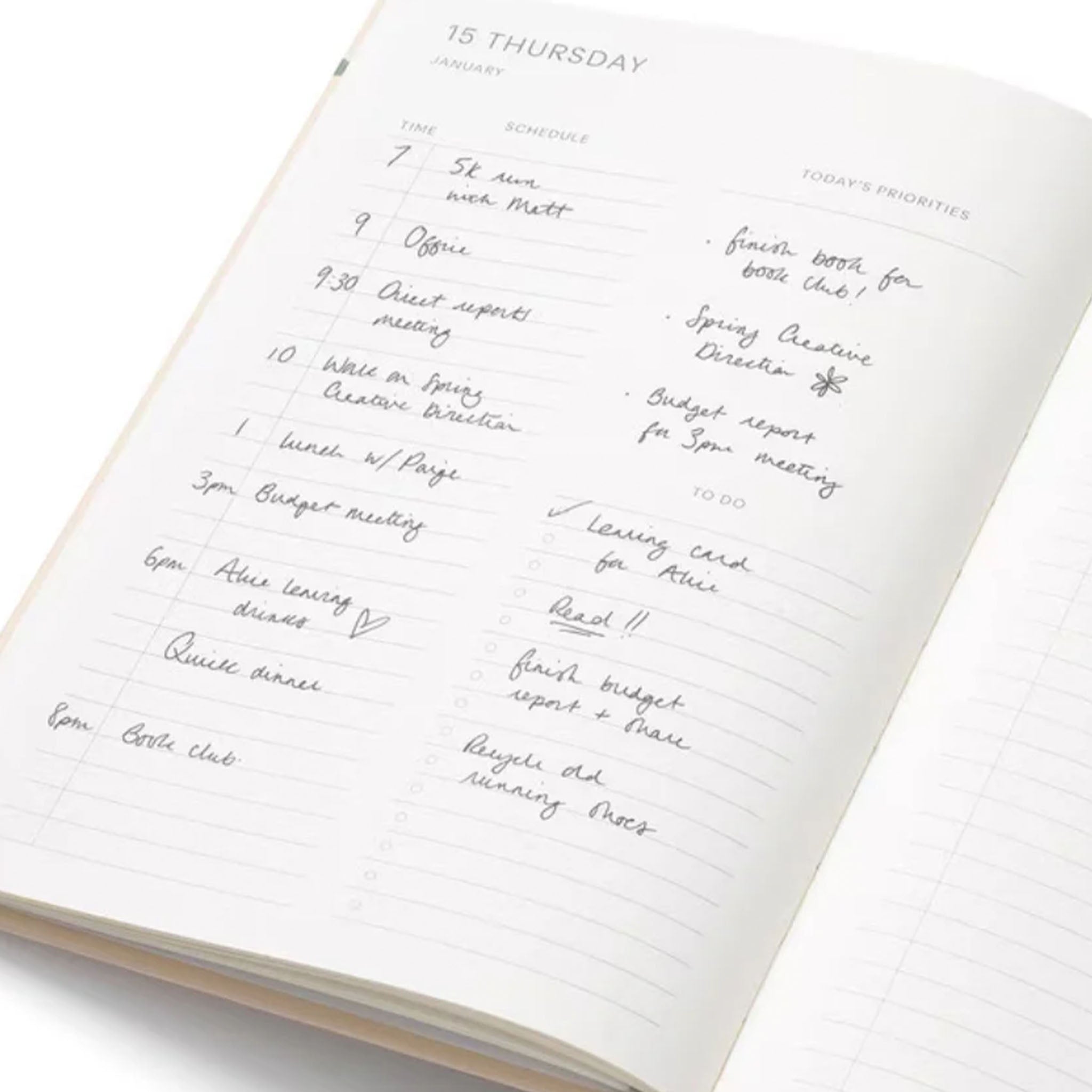 Open planner with handwritten daily schedule on a white background