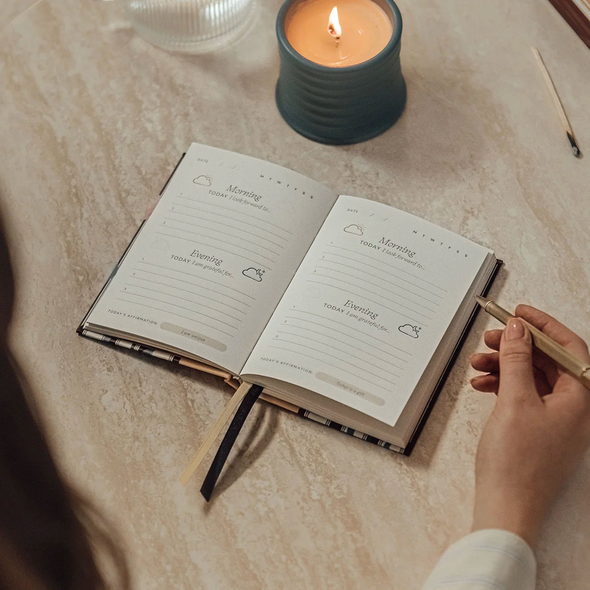 Open notebook with daily routine entries on a table next to a lit candle