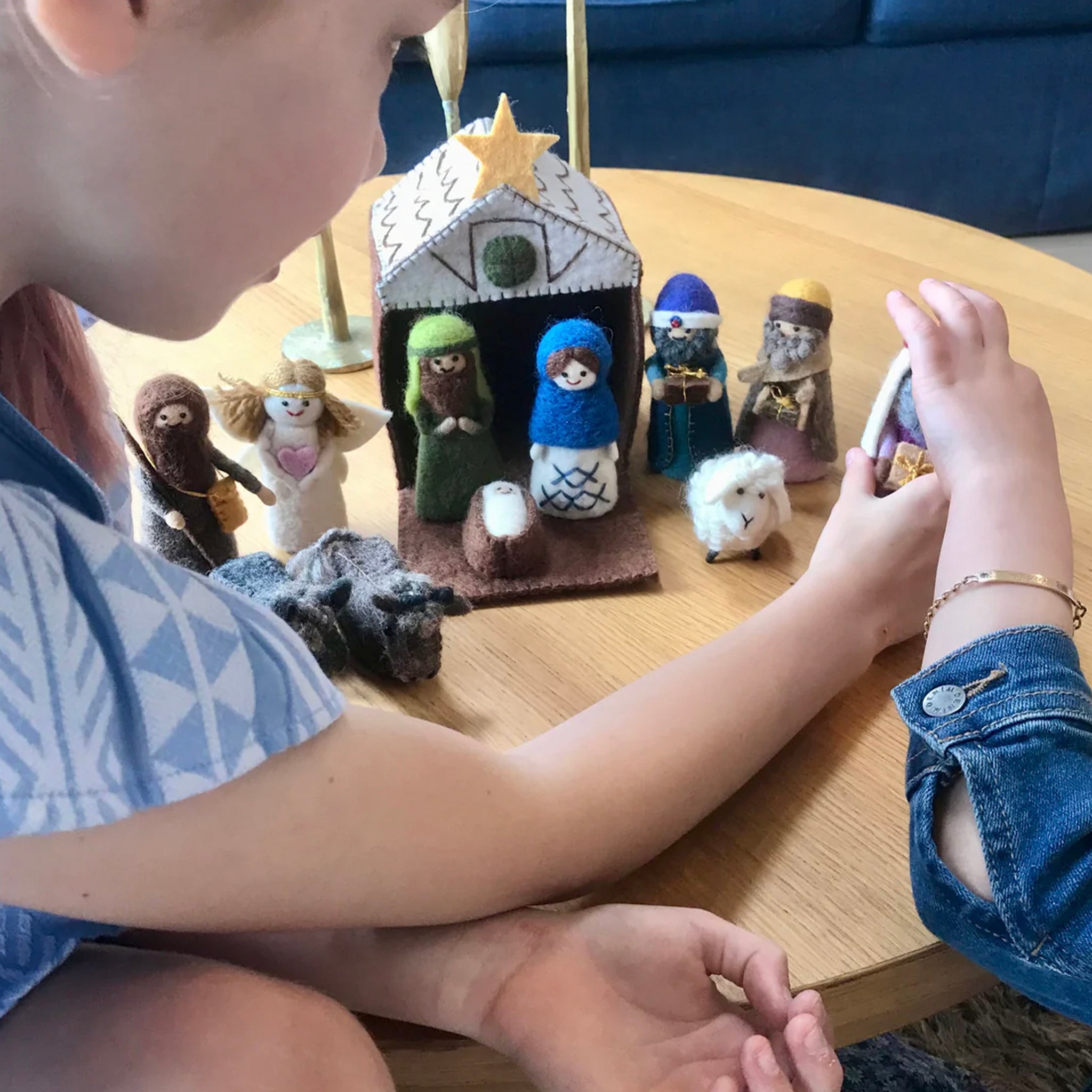 A colorful handmade felt nativity set featuring various characters including the three wise men, baby Jesus, Mary and Joseph, an angel, shepherd, sheep, and two donkeys, with a felt manger.