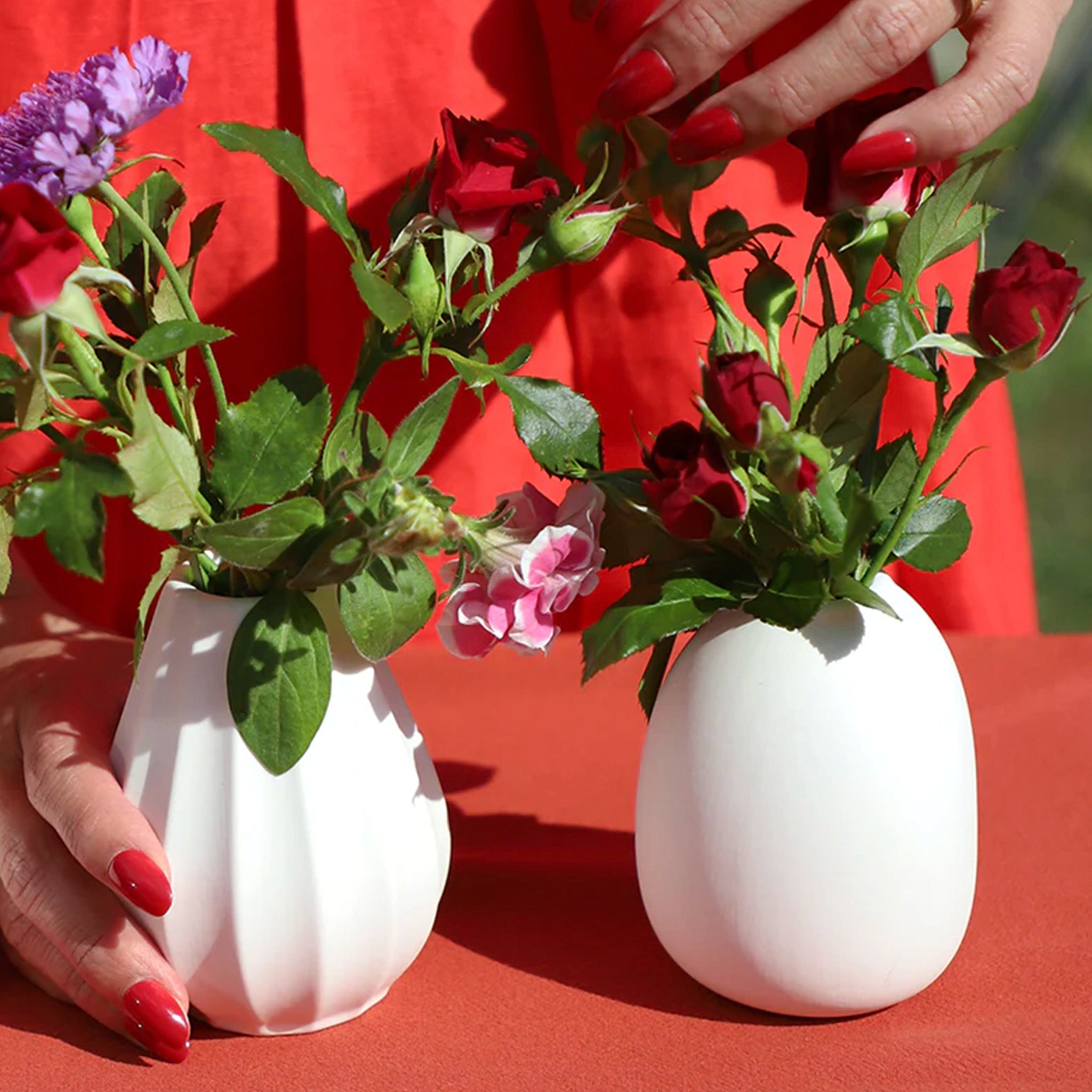 Two white vases with flowers on a red background