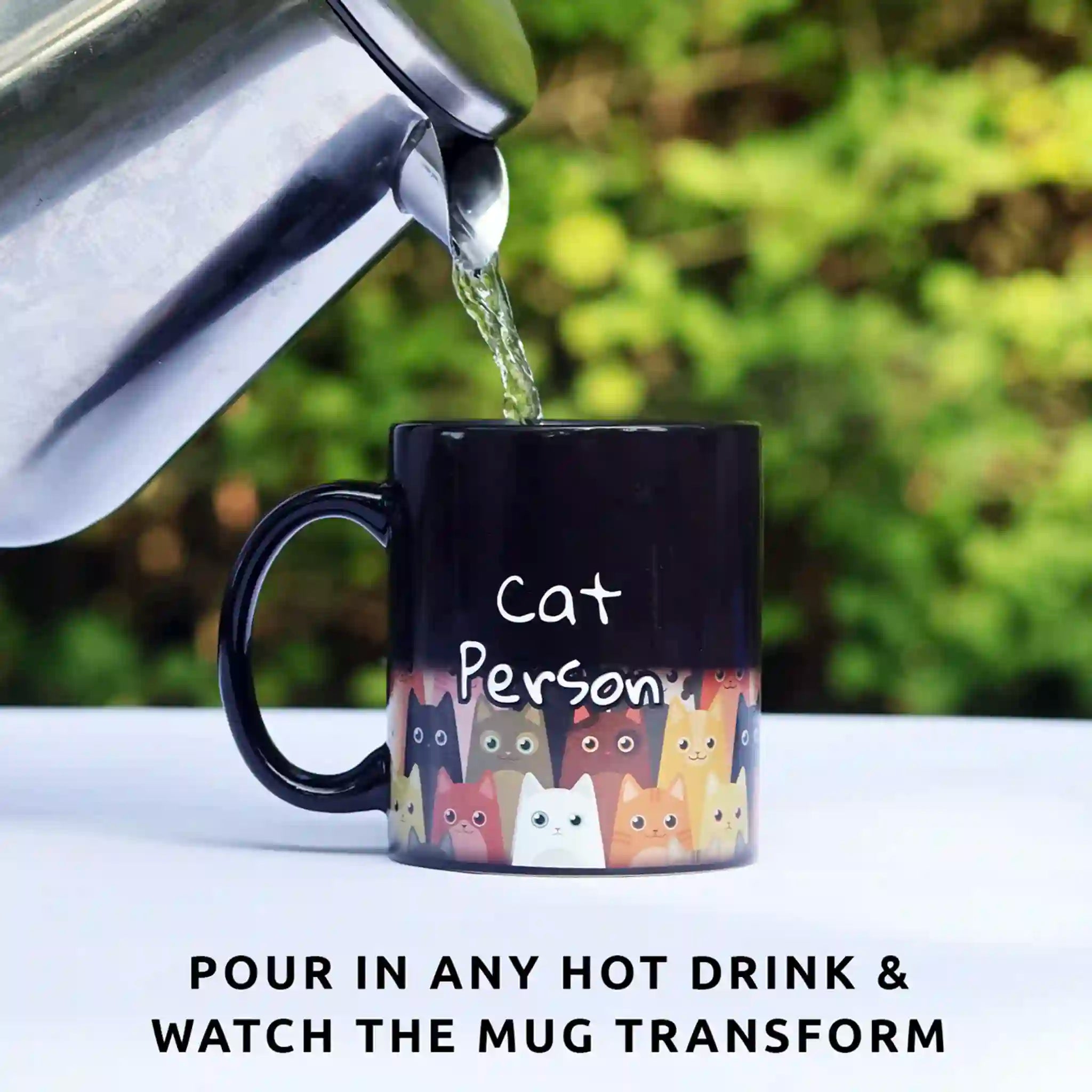 Black mug with cat designs being filled with hot water, outdoors.