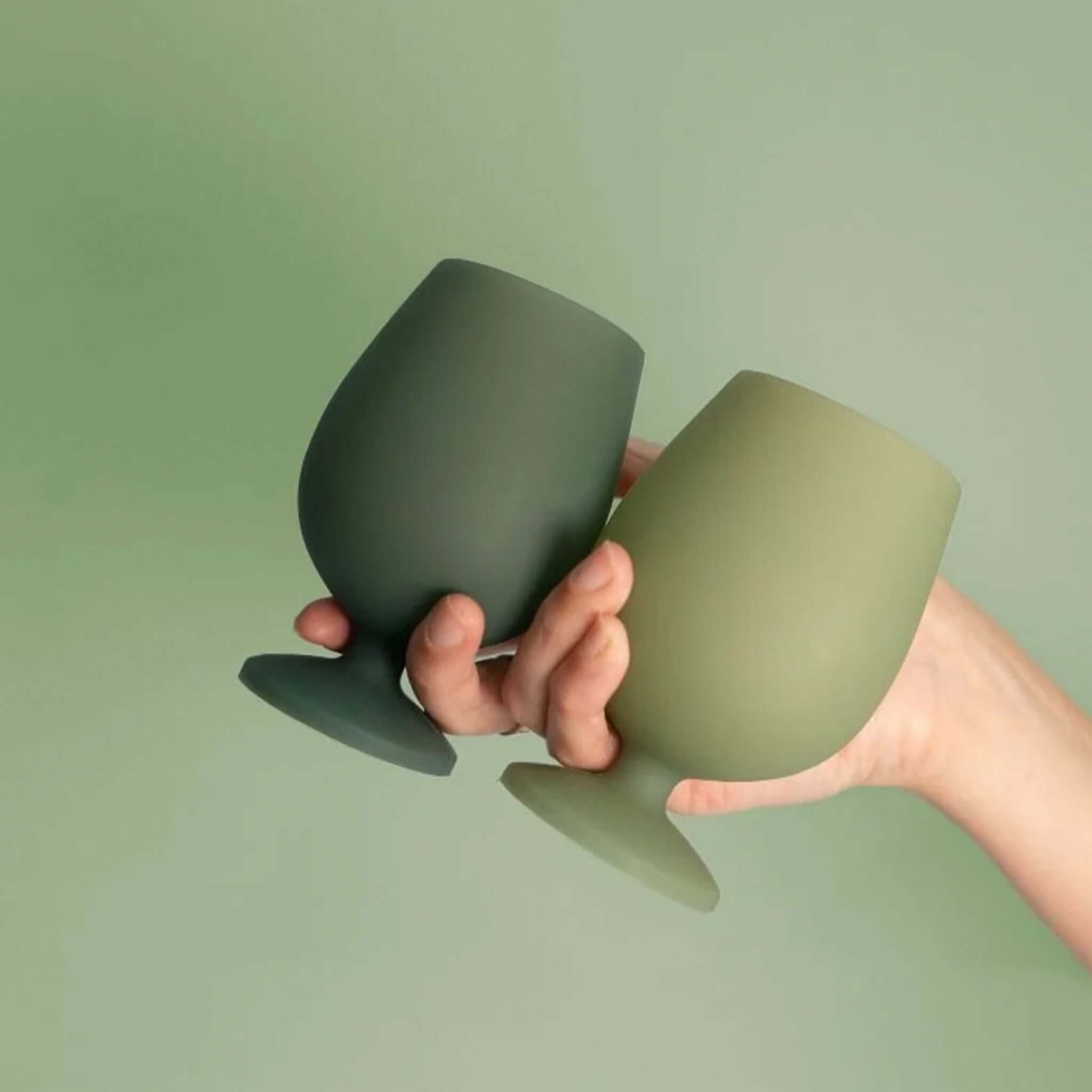 Porter Green Stemm Unbreakable Wine Glass Set - Sage & Olive in hand, featuring silicone glasses in sage and olive colors.