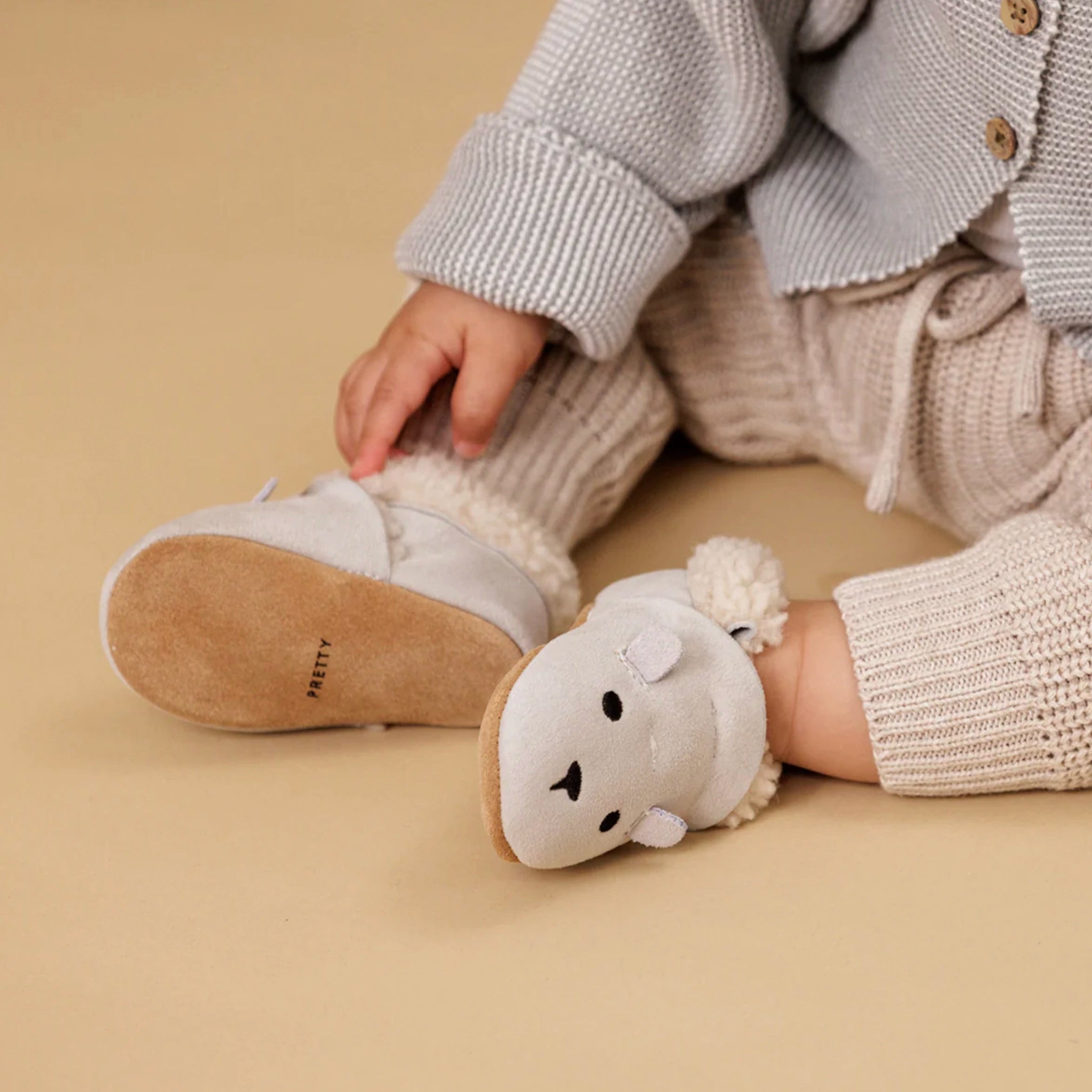 Child wearing white slippers with bear design on a beige background