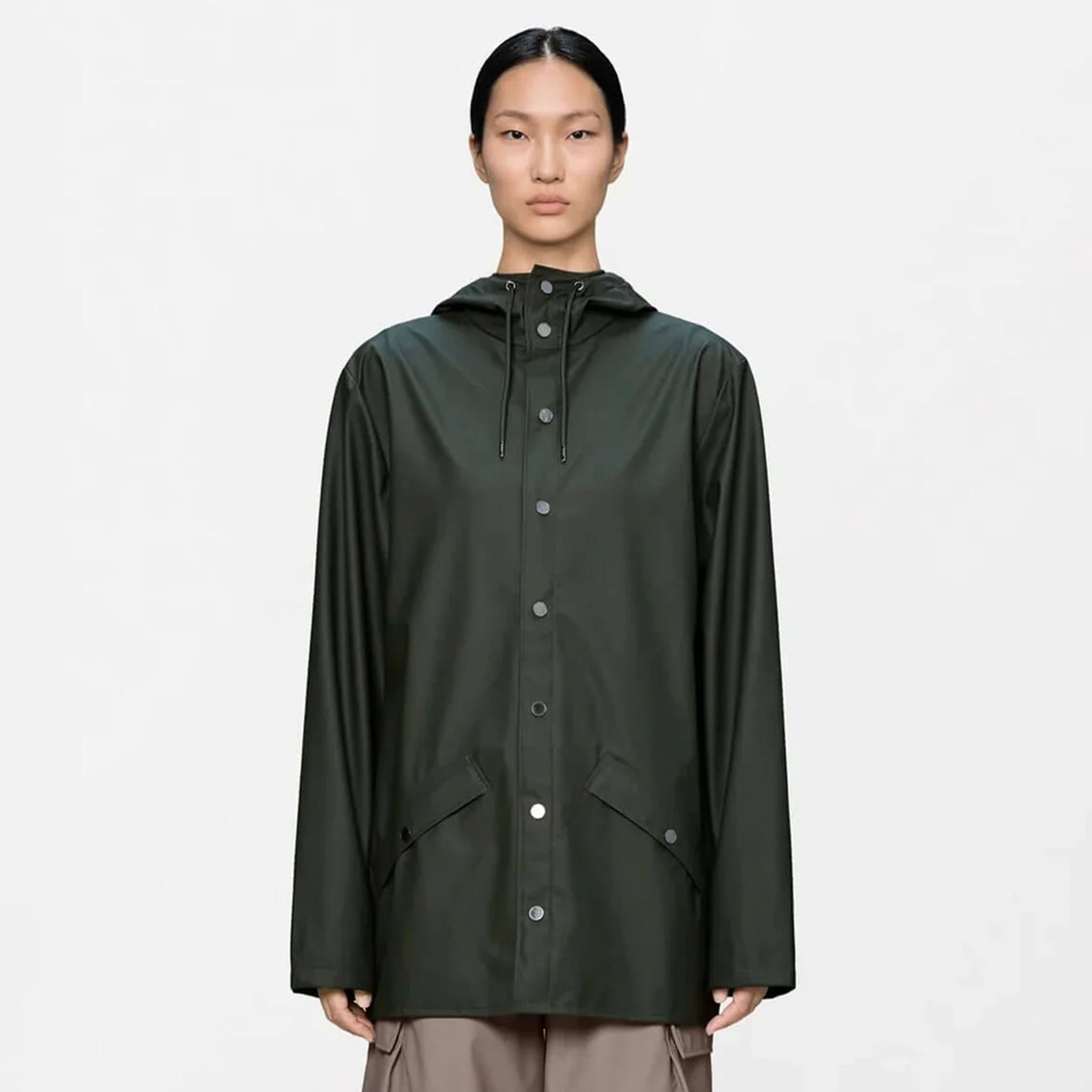 Rains Jacket - Green worn by a model, featuring a minimal design with adjustable hood and snap-front closure.