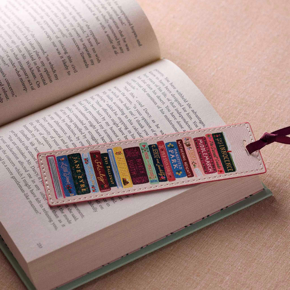 Rifle Paper Bookmark - Ladies Night Book Club placed in an open book, showcasing classic titles on a colorful bookmark.