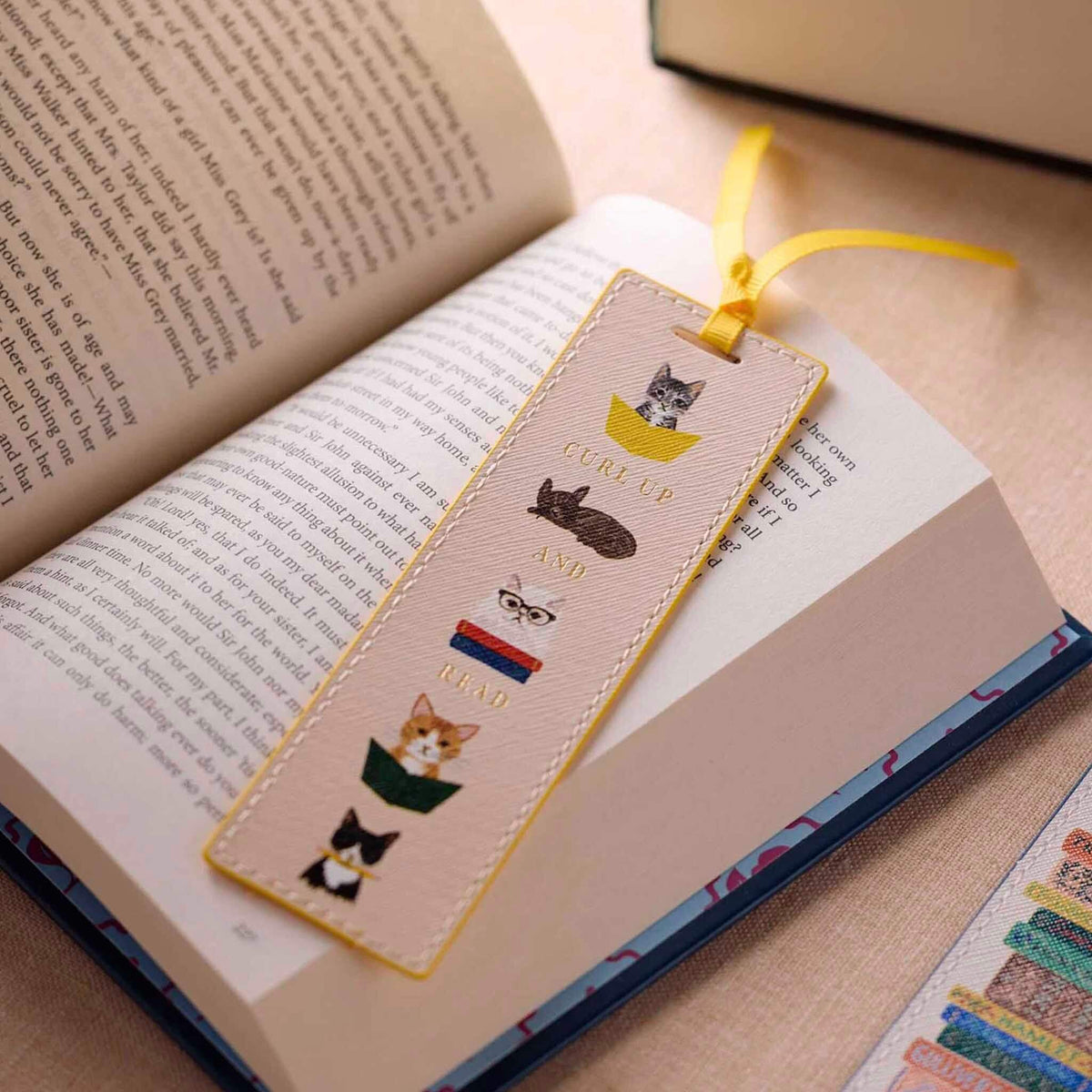 Rifle Paper Bookmark - Studious Cats featuring bookish cats and yellow grosgrain ribbon on a book.